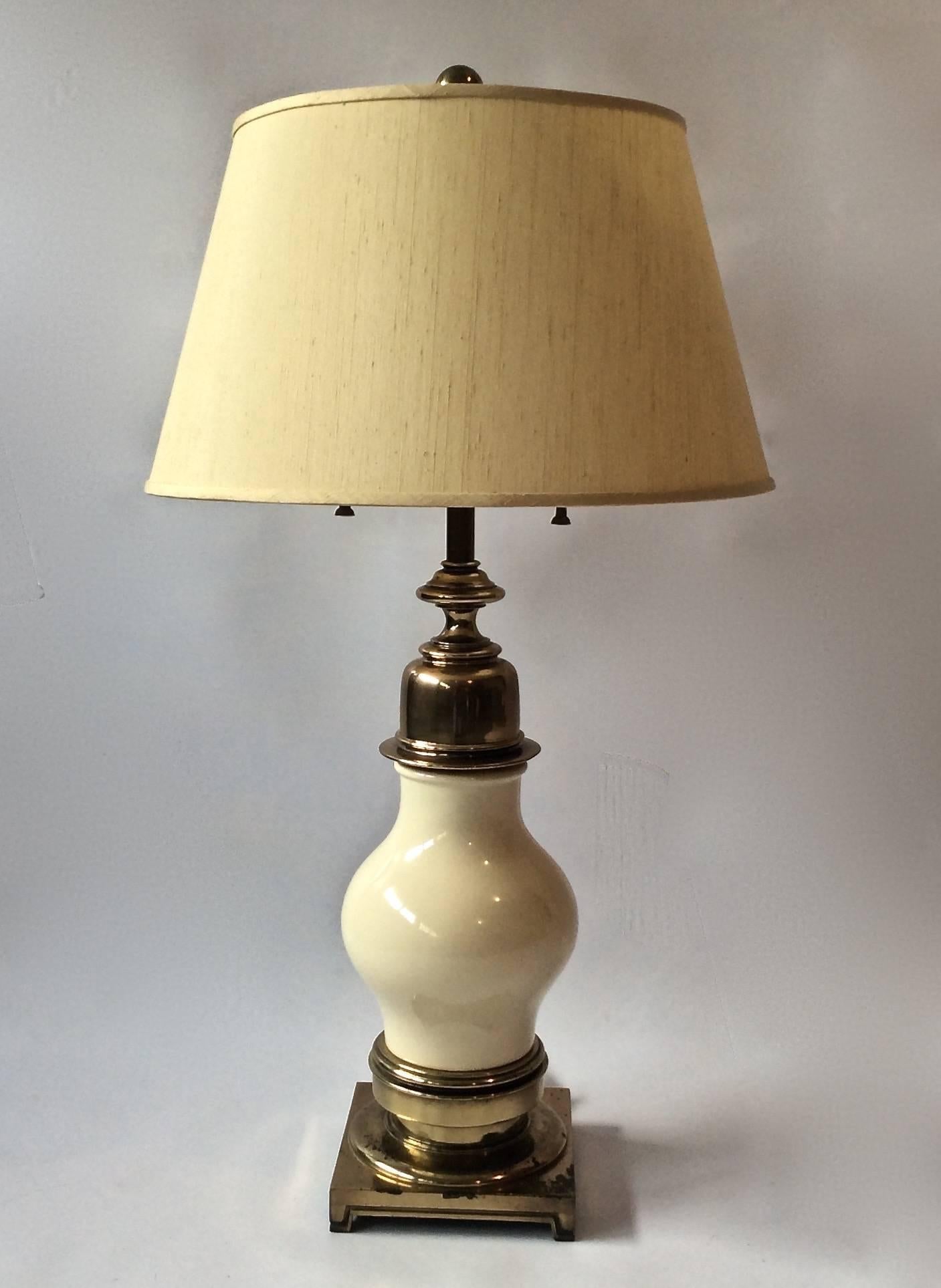Pair of large and impressive table lamps in ivory ceramic with solid aged brass base and accents by Stiffel Lighting, American, 1950s. Double cluster socket, labeled 