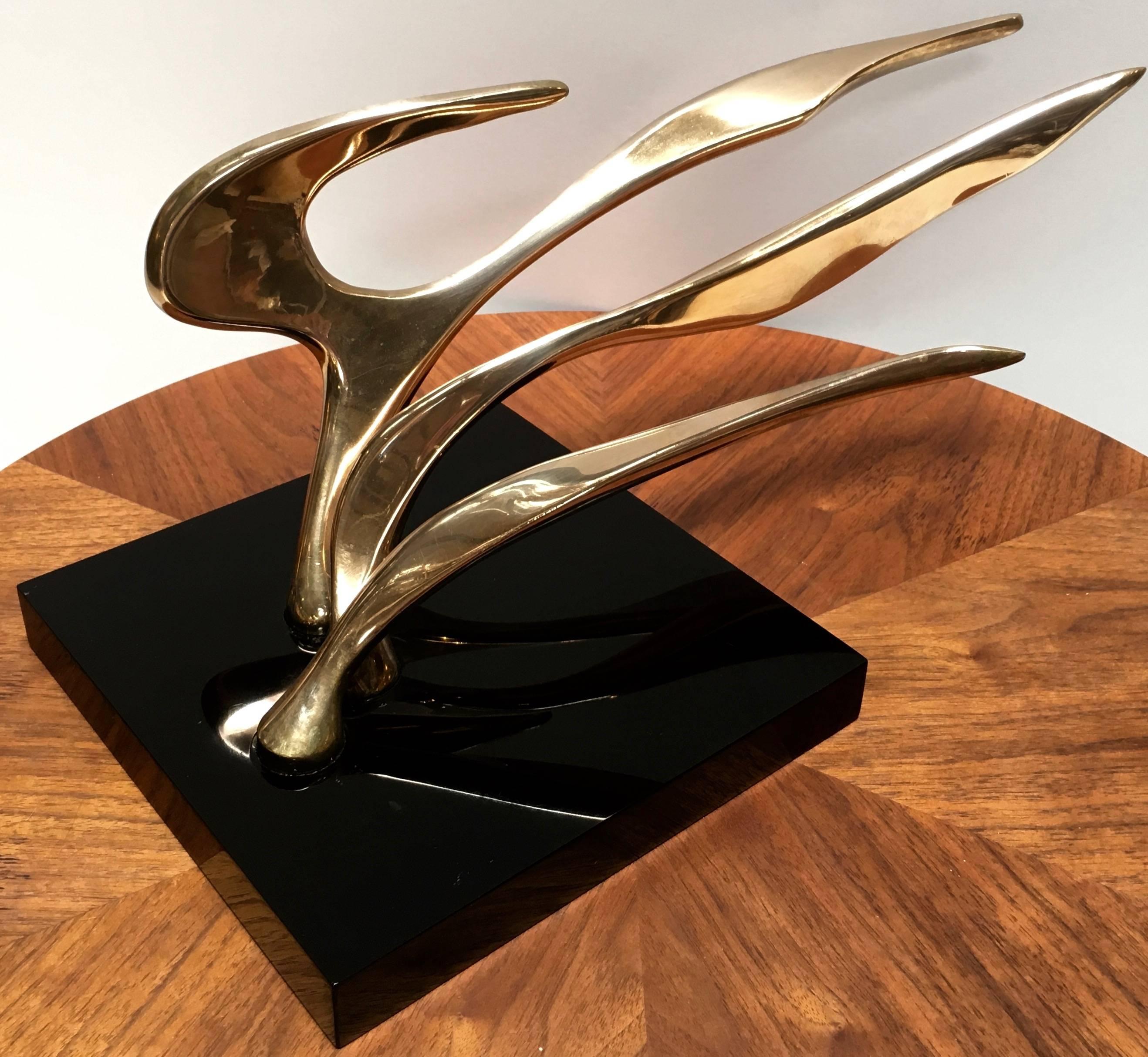 Three solid pieces of free flowing patinated brass, beautifully sculpted and inset into a black acrylic base. Each piece appears to be blowing in the wind and is removable and interchangeable for several different looks to this wonderful sculpture.