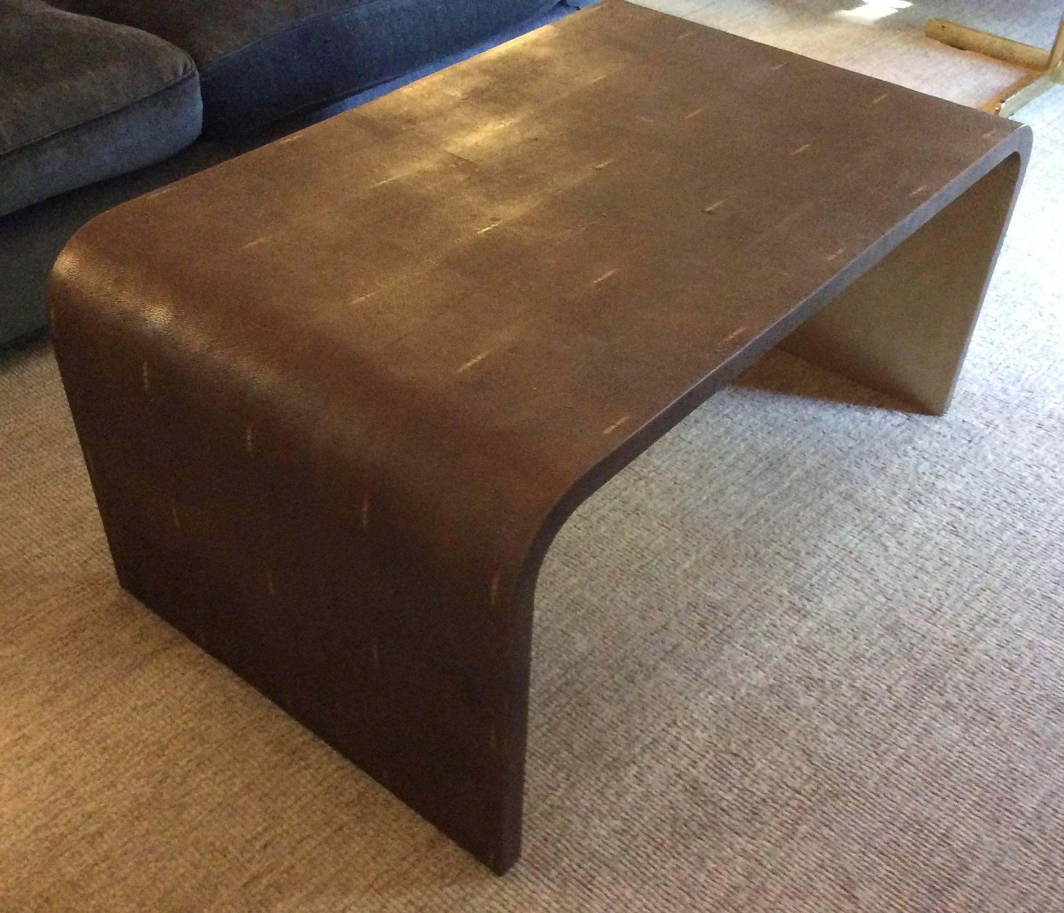 The Art Deco period inspires this coffee table with a graceful waterfall edge and a leaf finish underneath. The leather shagreen finish is cocoa chocolate brown.