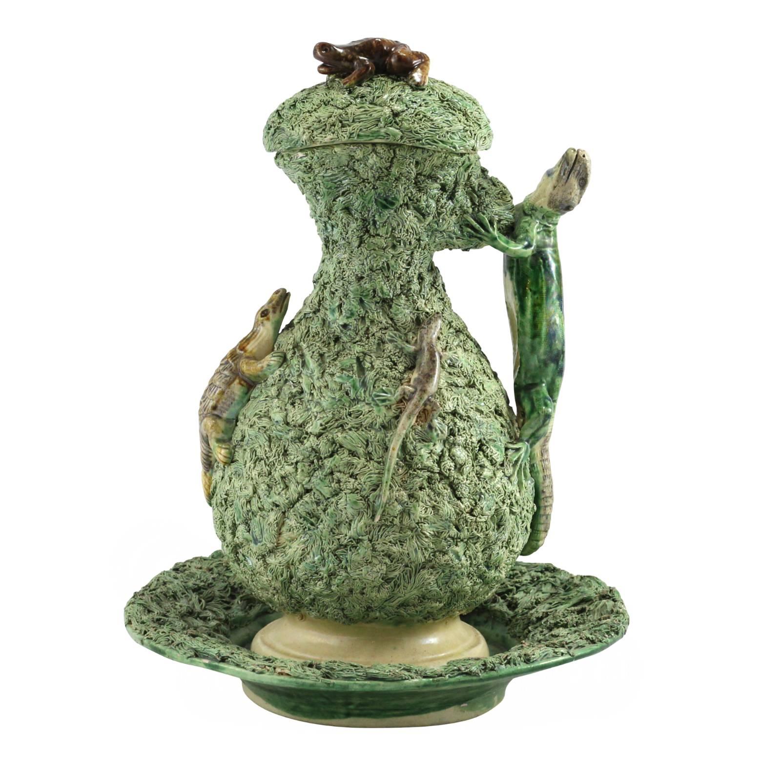 This 19th century lidded jug and bowl from Portugal is designed in the style of famous French potter, Bernard Palissy. Standing 32cm high, this fantastical piece is decorated with a green base, resembling moss, and adorned with frogs, insects and a