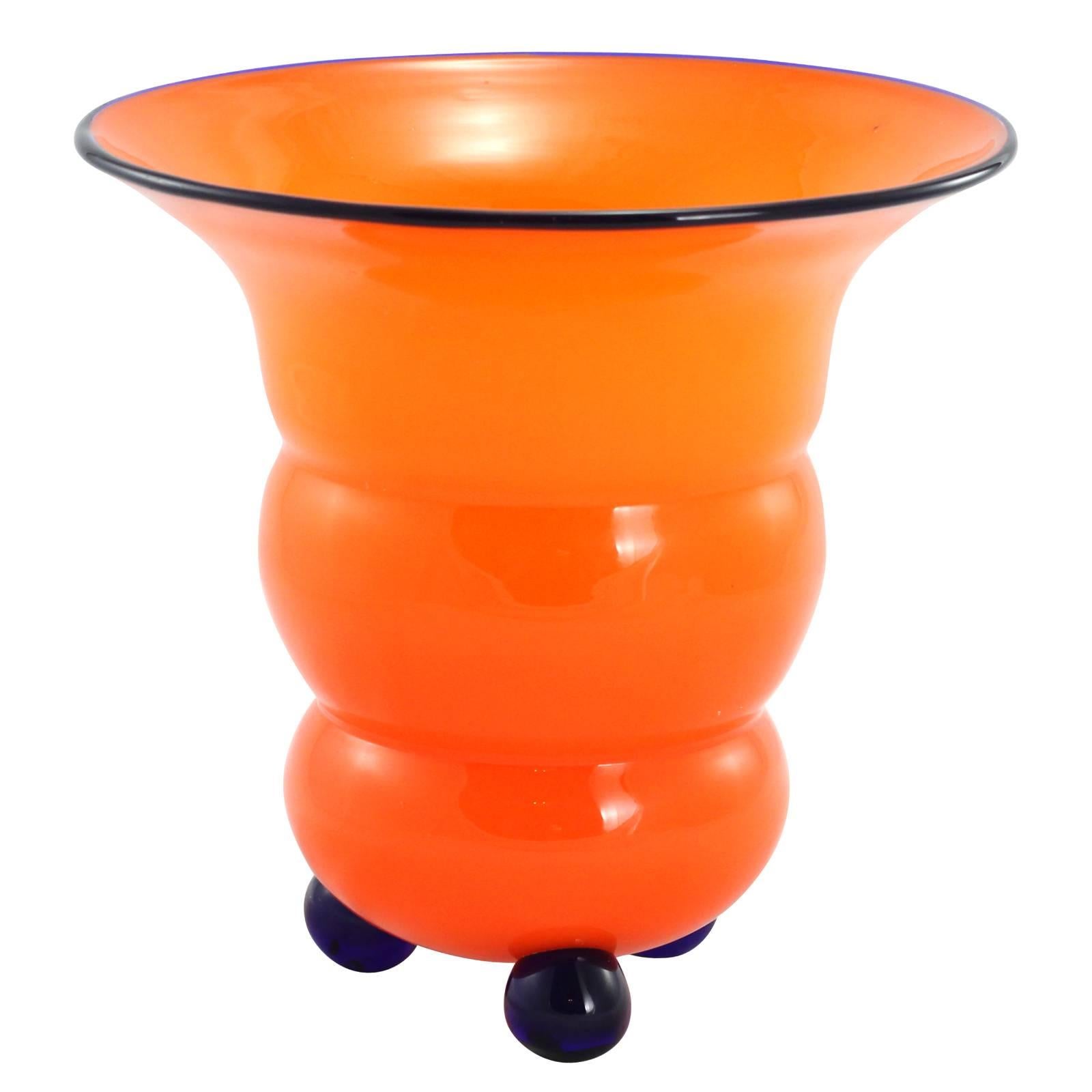 An early 20th century Art Deco ribbed tango glass vase by Loetz. Featuring a bold orange ground, with three cobalt blue ball feet and an applied cobalt blue rim.