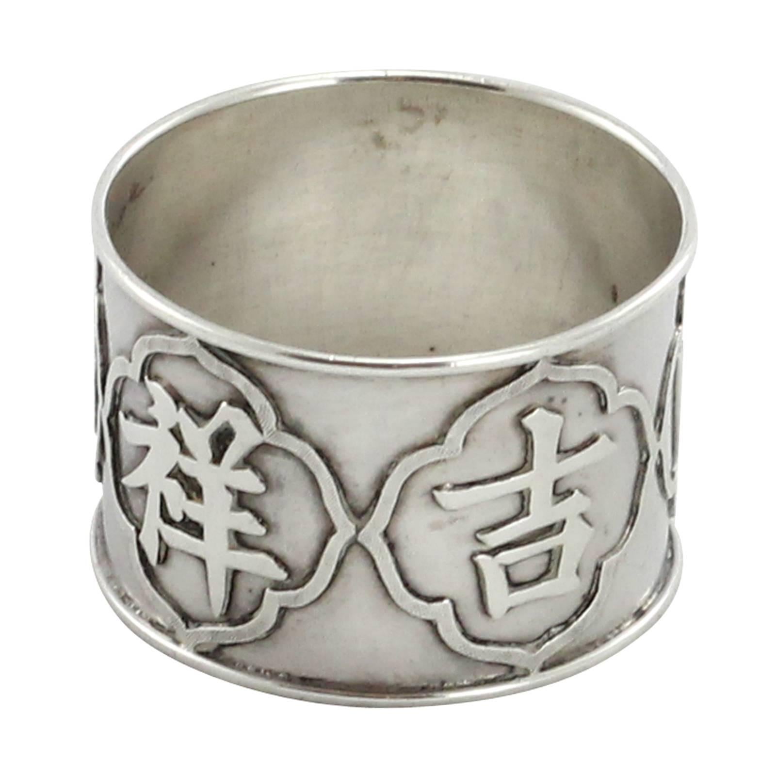 A Chinese Qing Dynasty export silver napkin ring from Shanghai retailer Woshing. The piece features four Chinese characters and a blank shield, assumedly for a monogram.