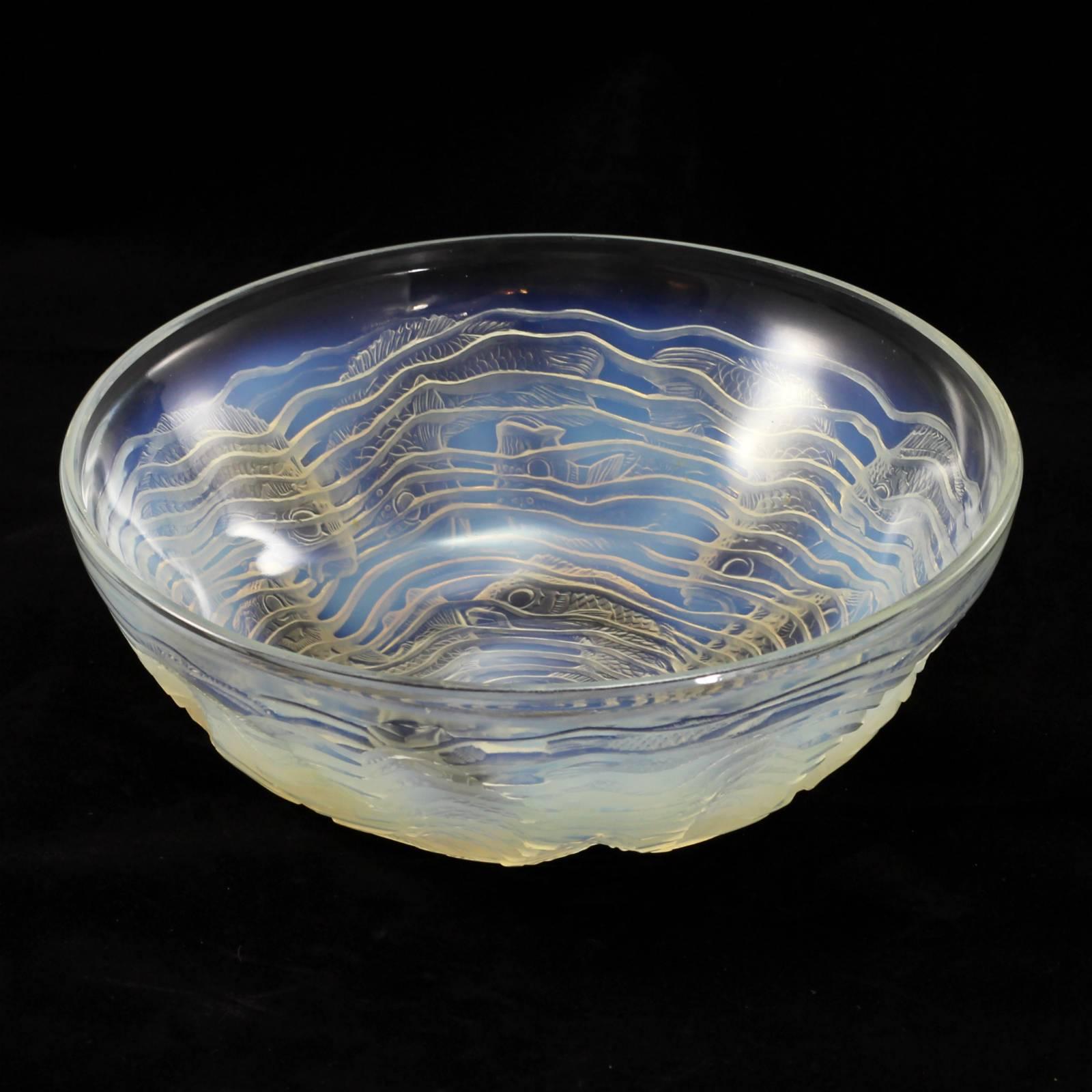 An early 20th century Art Deco glass bowl in the 'Dauphin' pattern by René Lalique. The opalescent glass displays varying hues of blue and green throughout the aquatic motif of the bowl. The piece is decorated with a spiral 'wave' which circles the
