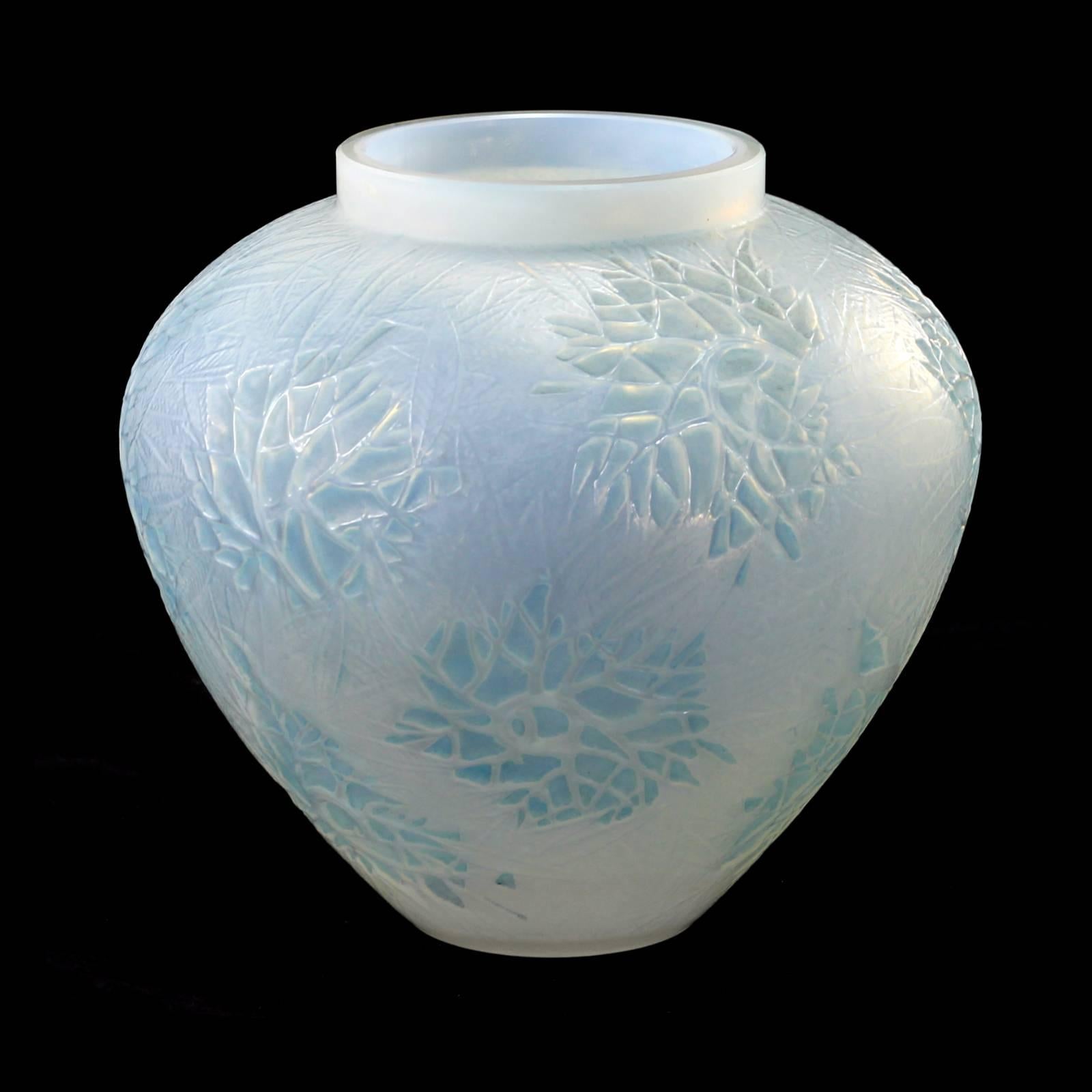 An early 20th century Art Deco glass vase completed in the 'Esterel' pattern by French glassmaker René Lalique. The white opalescent glass is decorated in an asymmetrical leaf pattern, which has been patinated in a light blue color. The piece is