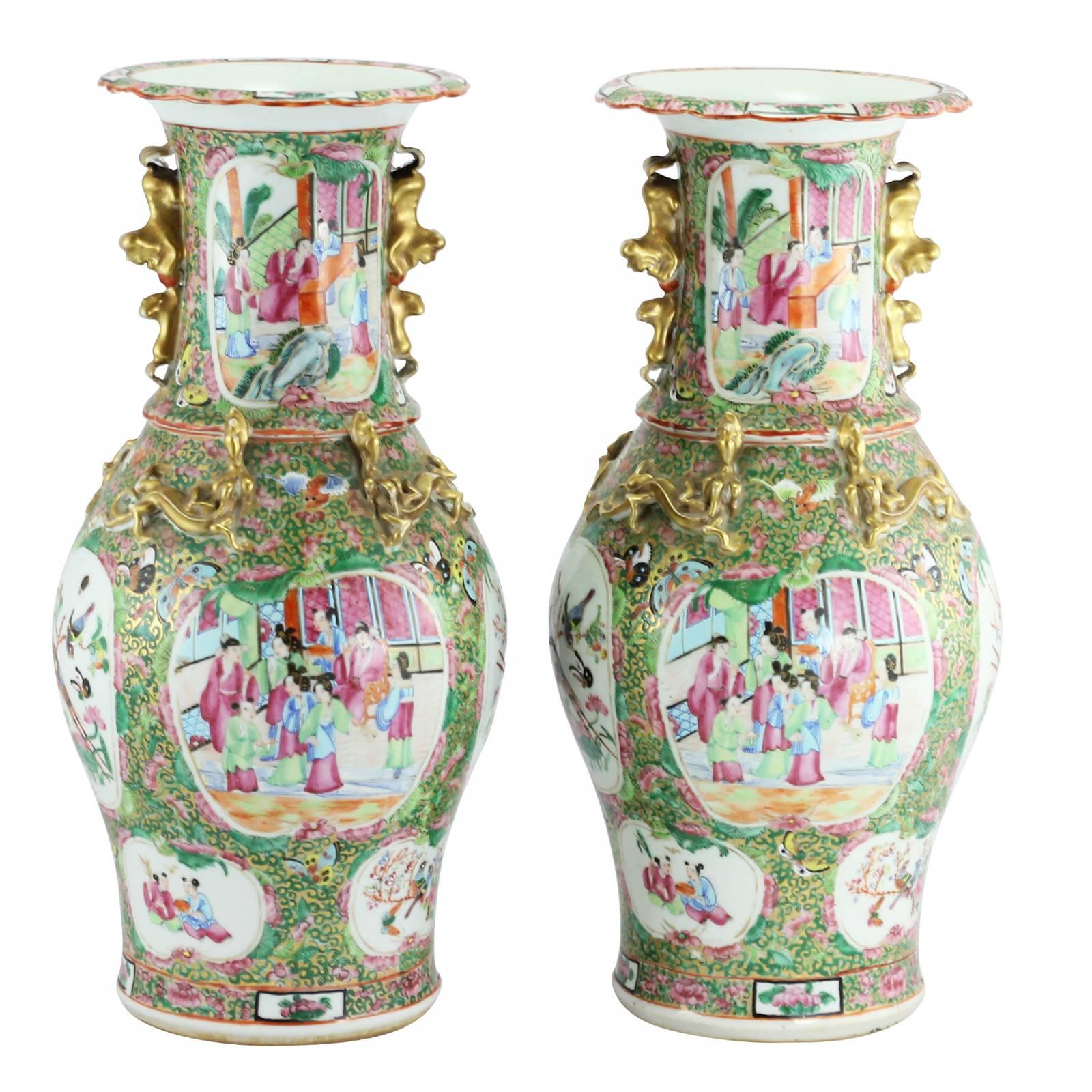 A pair of late 19th century Chinese Qing Dynasty famille rose vases. On each vase, the baluster shaped body features four main panels, alternating between scenes of birds, insects, and flora; and scenes of people in a pavillion. A similar