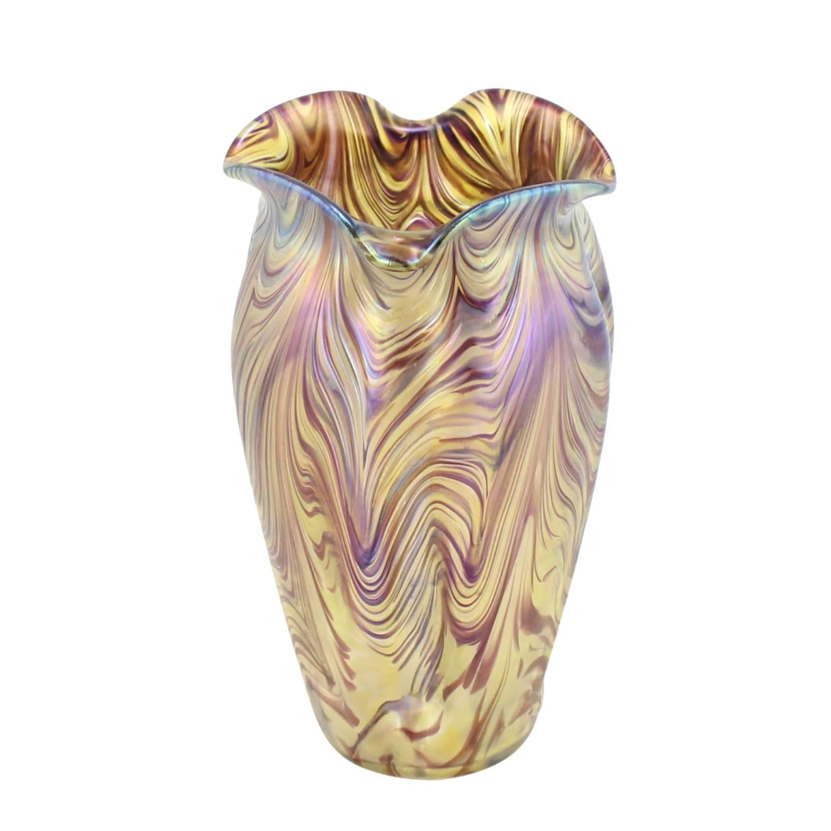 An Art Nouveau handblown vase in the swirl decor featuring churning stripes of gold and purple in varying thicknesses applied over a clear glass base. The bottom features a ground pontil mark.