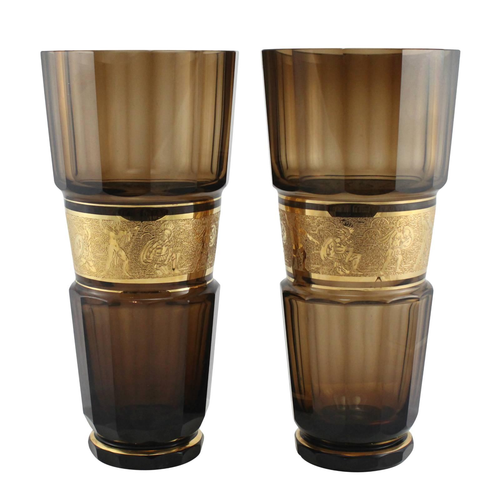 A pair of early 20th century smokey quartz colored faceted Bohemian glass vases by Moser Glassworks. Decorated with gold gilt banding, and a gold gilt neoclassical themed frieze around the middle of each vase.