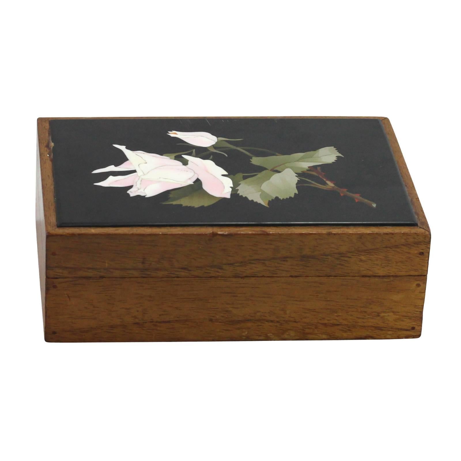 An Italian, wooden jewelry box from the 1920s decorated with a flower made using the Pietra Dura technique.

Pietra Dura is the Italian method of using cut and fitted, highly polished colored stones to create an image, inlaid in another