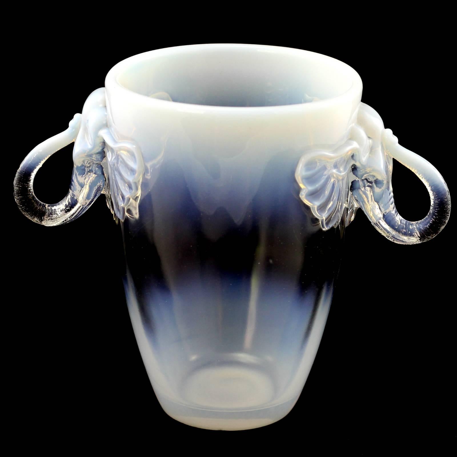 This whimsical vase doubles nicely as a champagne bucket with handles modelled as elephants with flared ears and a rearing trunk. The opalescent quality of the class receeds to a clear glass in the centre before fading again to opalescent for the