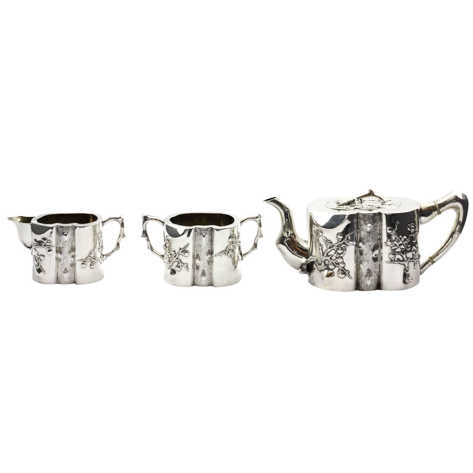 A late 19th three-piece Chinese export coin silver tea service by Hong Kong retail silversmiths, Wang Hing. The piece features a heavy prunus motif, with the centre of each piece representing the grain, whilst the spout and handle represent the