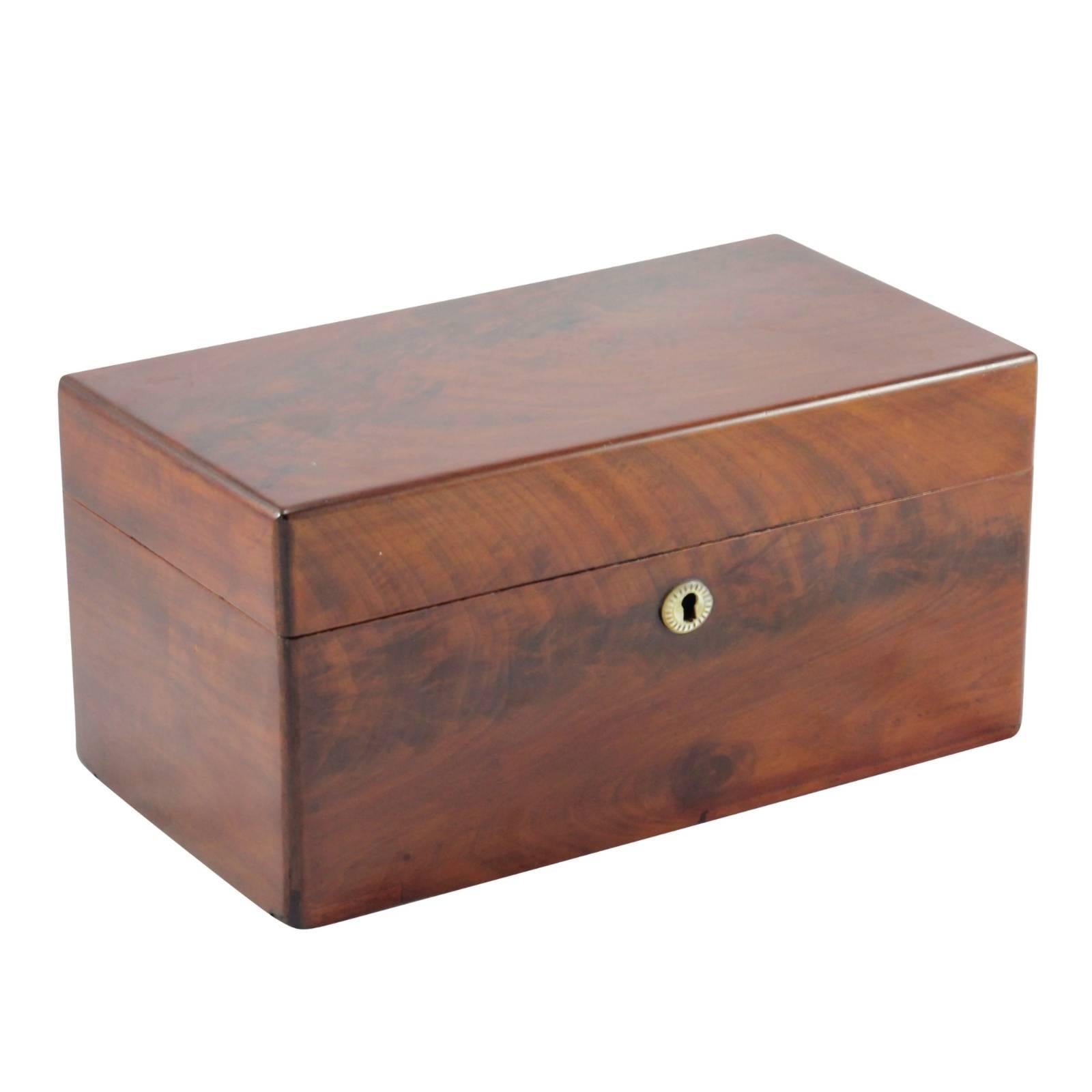 This rosewood tea caddy contains two removable compartments for loose tea with hinged lids. It also contains a later pressed amber glass mixing bowl. The outer box features a mother-of-pearl escutcheon but has no key. The bottom of the box has a lot