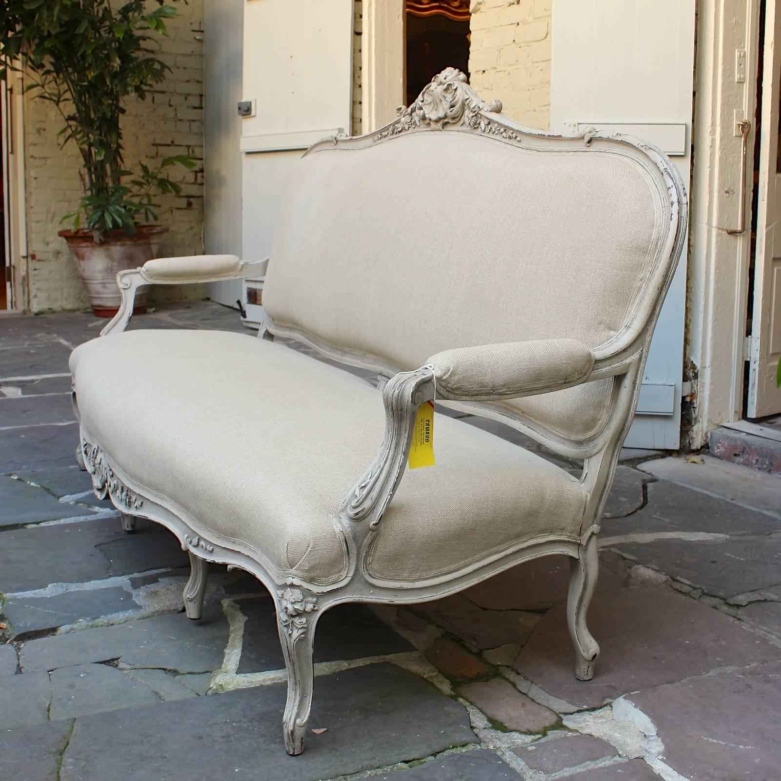 Early 19th century French canapé with rare detailed carvings and French paint, completely taken down and reupholstered in French linen.