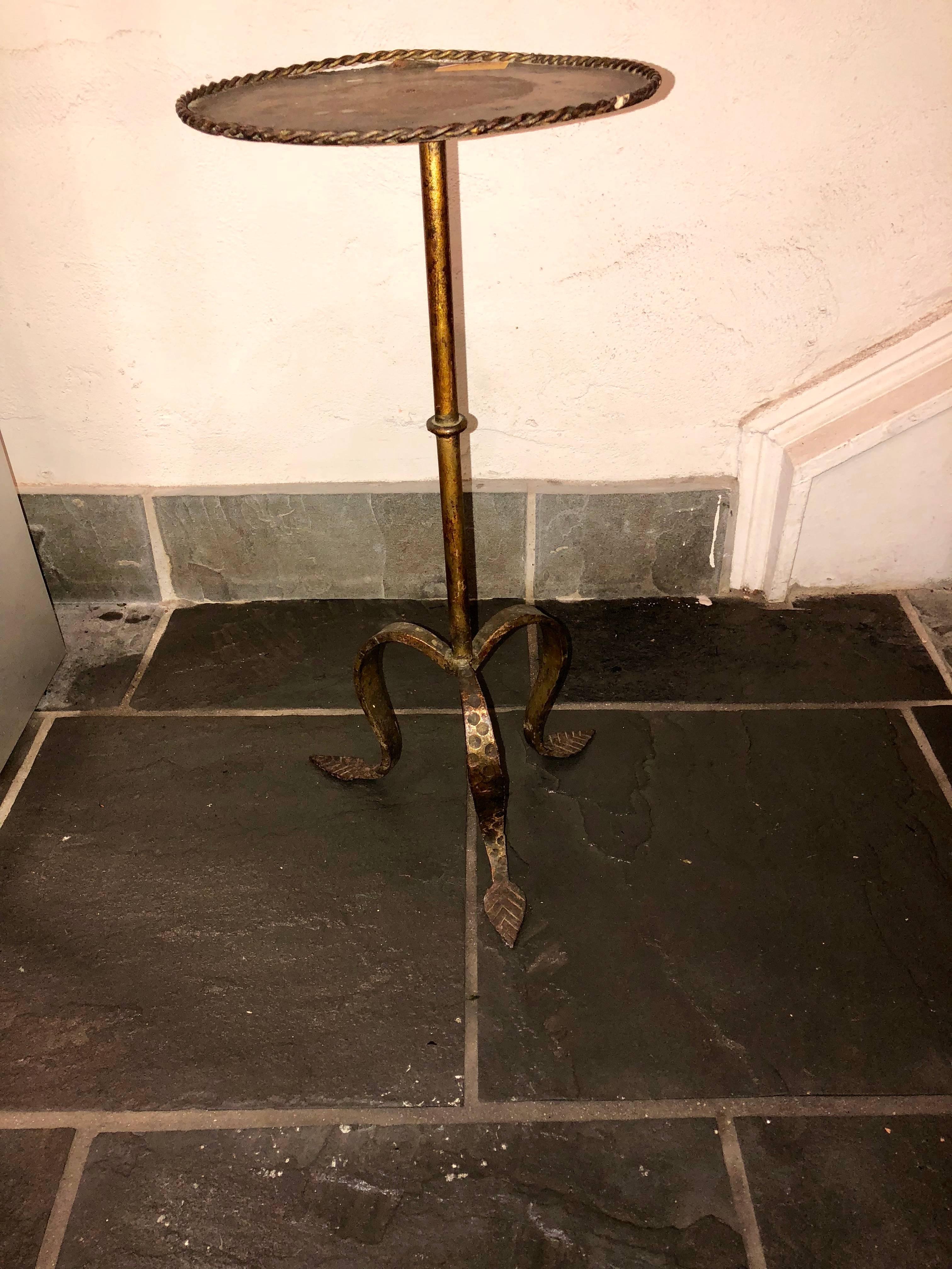 This vintage French martini table is a perfect piece to be nestled beside a canapé or bergère. This piece is made of iron and includes a braided trim and  teardrop-shaped leaf feet. This selection also has beautiful patina. 