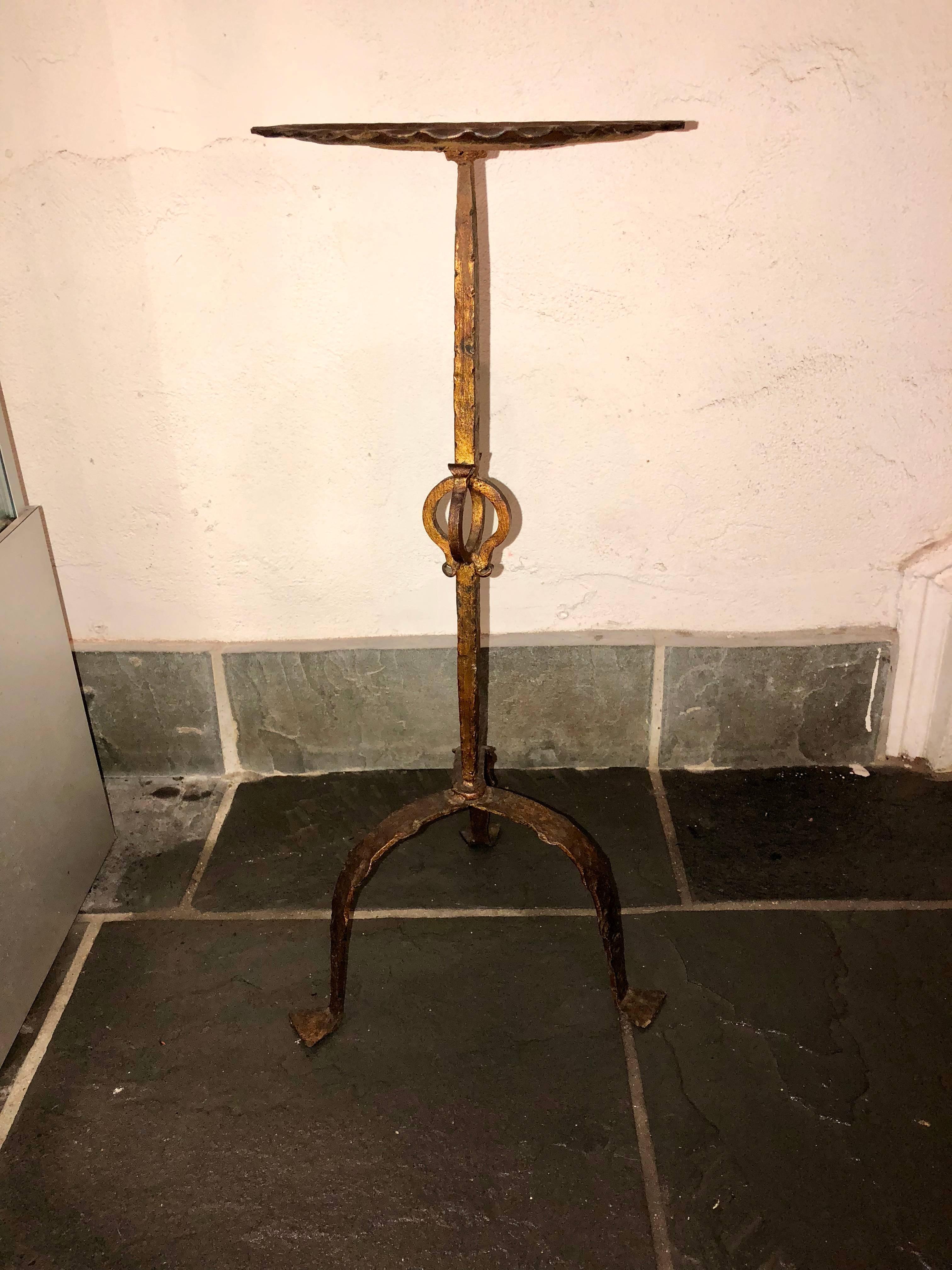 This vintage French martini table is a perfect piece to be nestled beside a canapé or bergère. This piece is made of iron and includes an enameled trim and  trapezoid-shaped feet. This selection also has a unique decorative stem and beautiful