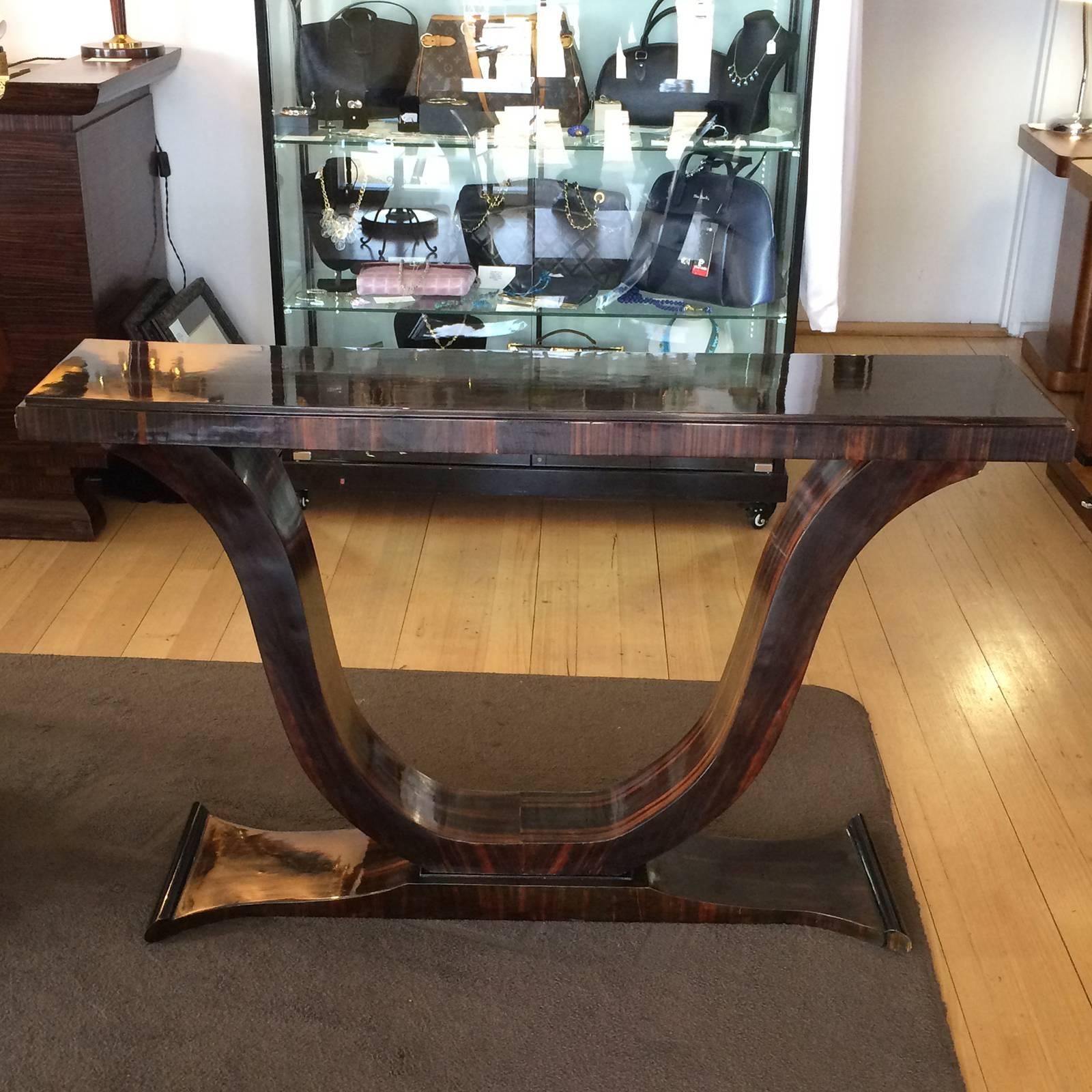 Art Deco style console table in lacquered Macassar wood. An amazing, iconic deco shape, with spectacular timber grain. All in a soft, aged patina. Dimensions are approximate: 131cm wide at top (34cm at bottom toes) x 30.5cm deep x 80cm high.
