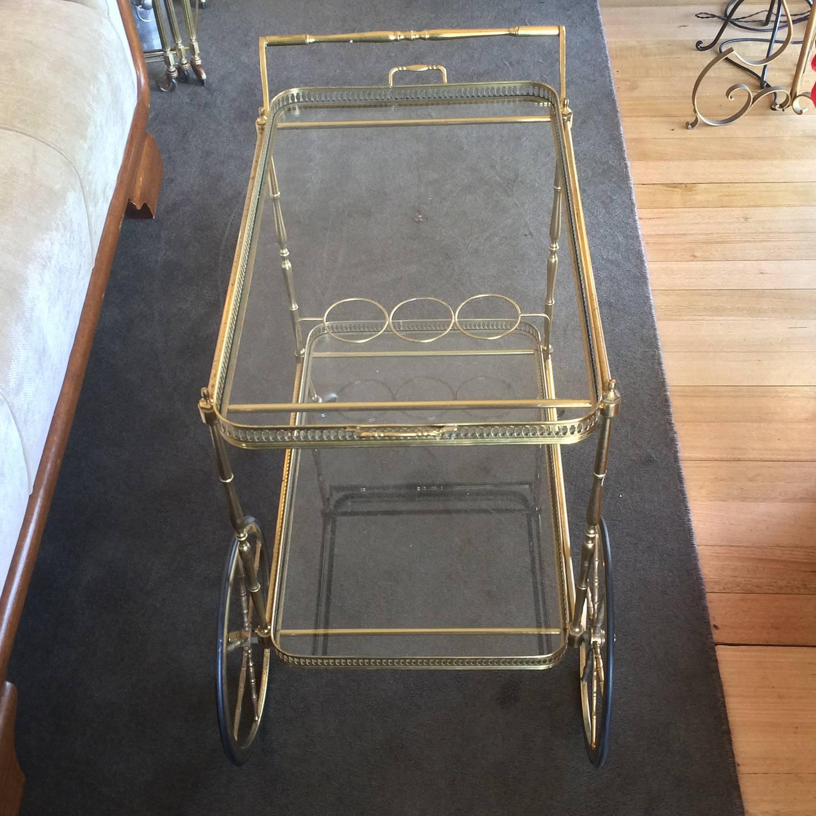 Midcentury French gilt rolling bar cart, complete and all in excellent condition, soft age patina. Gilt metal hubcaps small, black rubber rear wheels and larger ones to front, all perfect with no wear to rubber or losses; working well as designed.
