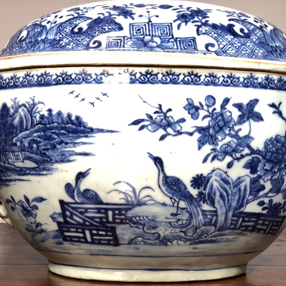 Large Chinese export blue and white tureen, in the Meissen style with baroque mask handles terminating in high feather headdress handles, the body painted with large exotic birds in fenced gardens within river landscapes, the lid painted with