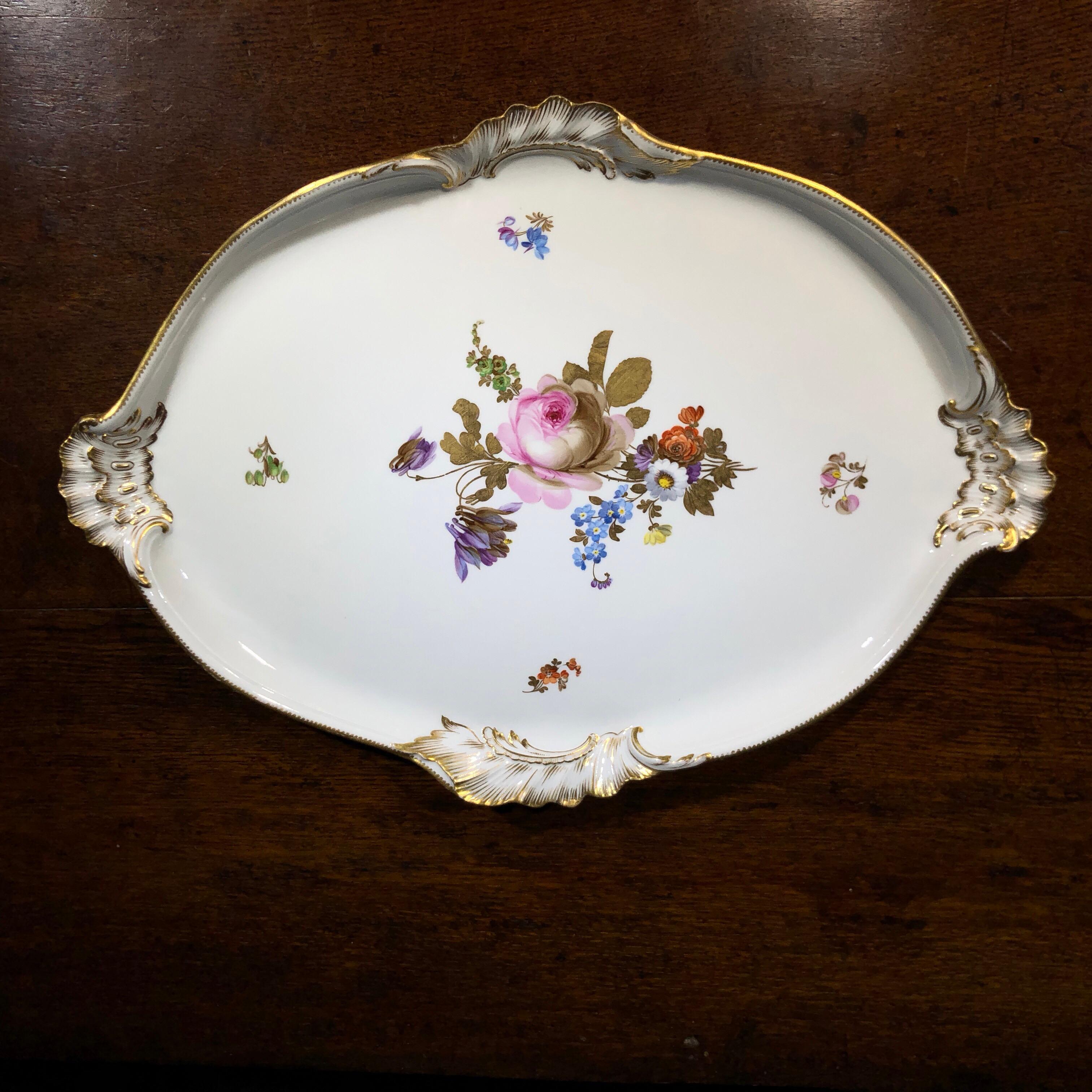 Meissen large oval tray, of Rococo form with scroll mouldings to rim forming handles, painted in the centre with a large flower spray including rose and aquilegia, the leaves in gilt.
Incised number, underglaze crossed swords,
circa 1870.

 