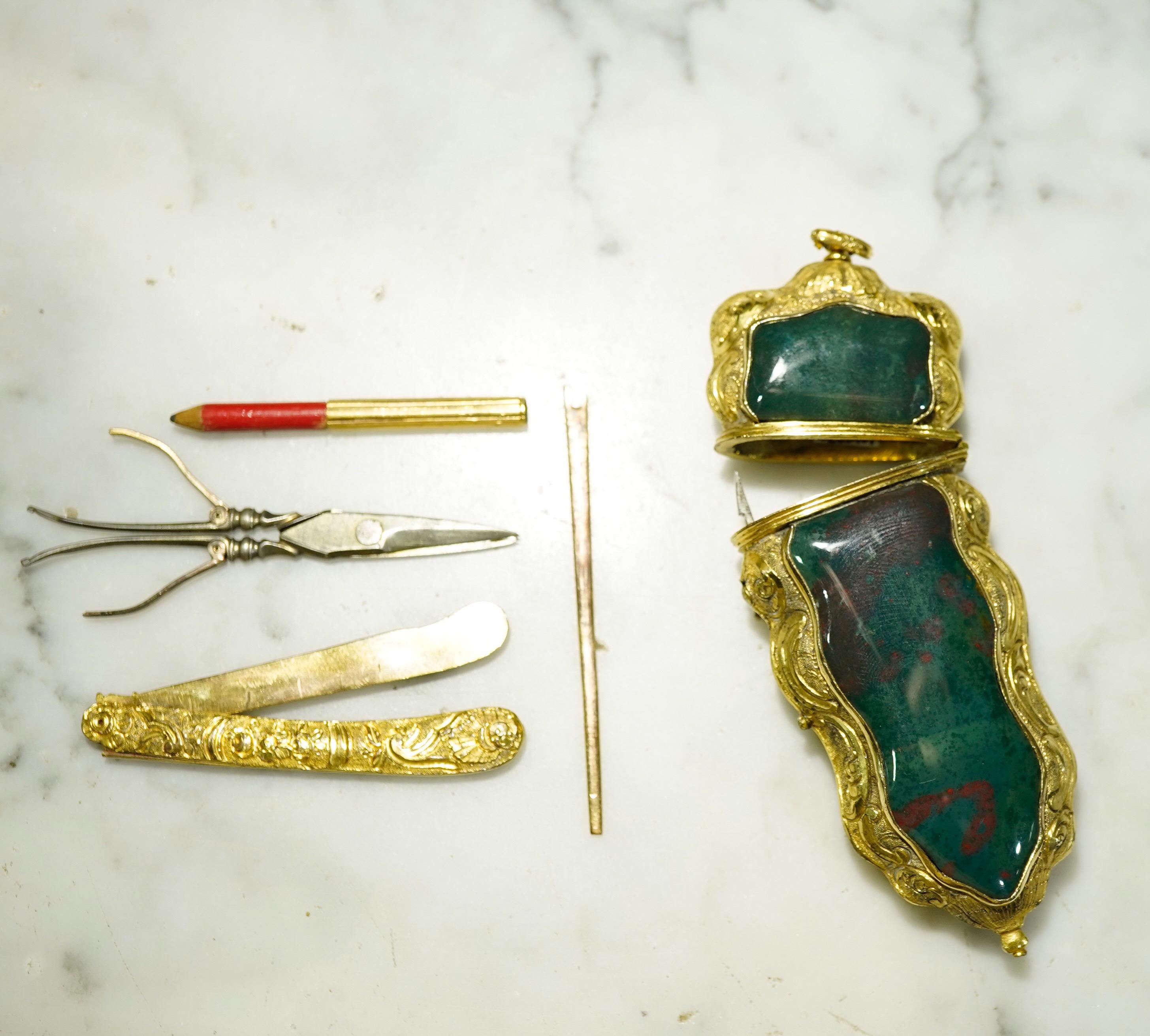 Superb quality gilt metal etui, the Rococo form with central bloodstone specimen and finely tooled mounts, the interior with partial contents including folding knife, scissors, pencil, bodkin, aid-de-memoir, missing tweezers,

circa 1750.