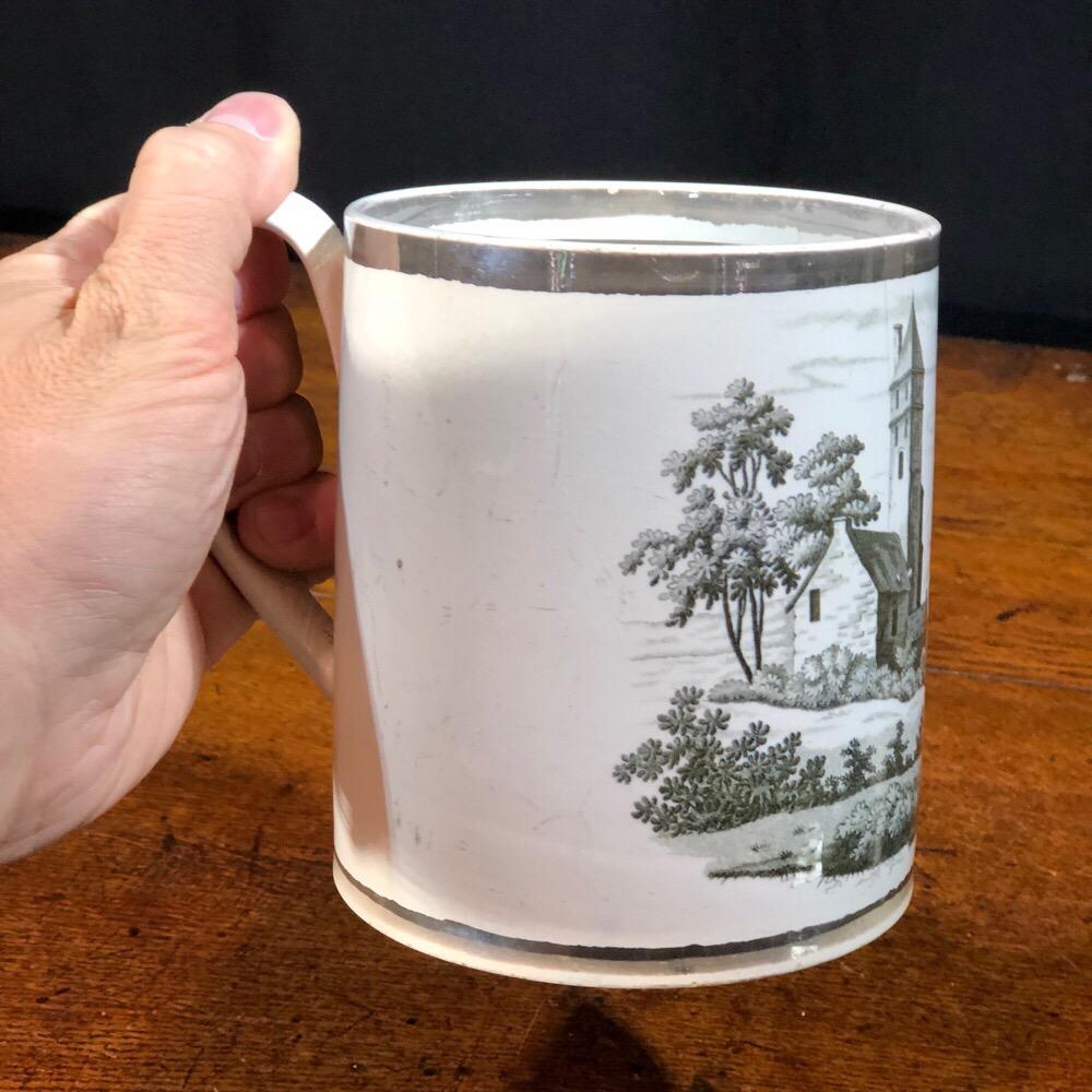 Pearlware porter’s mug, the finely potted form with large scale bat-print of a towered house in a mountainous landscape, within platinum lustre line borders, the handle with a black enamel feather to handle,

circa 1800.