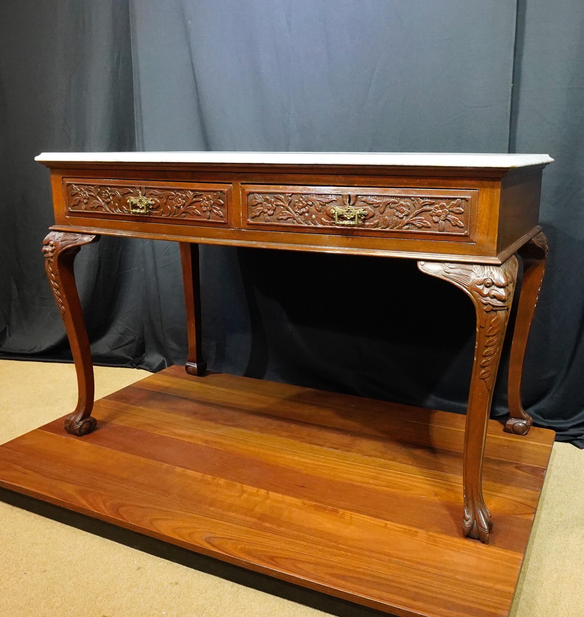 Chinese export mahogany hall table, with mottled white marble top above twin drawers carved with prunus, the cabriole style legs carved with dragons.
South-East Asian, probably, Malacca,
circa 1910.

Purchased mid-20th century in Malacca as