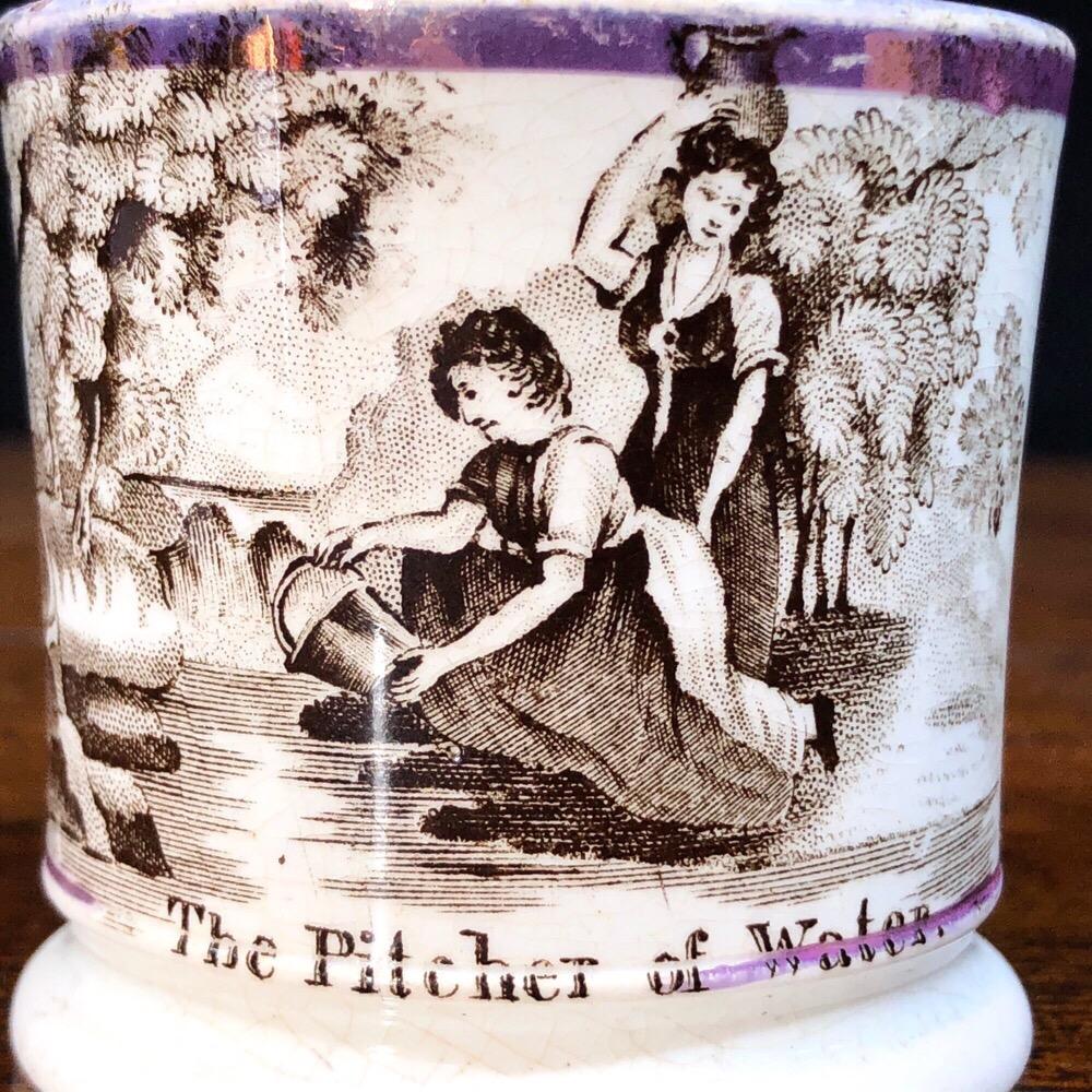 Staffordshire Pottery child’s mug, printed in black with children by a stream, titled ‘Pitcher of Water’, with purple lustre rim,
circa 1830.