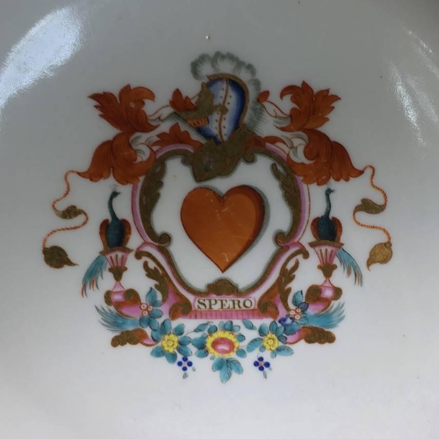 Unusual English hexagonal plate, decorated in the Chinese Export manner with a central armorial device consisting of a large heart in a rococo cartouche, titled ‘SPERO’ beneath, a knight’s helmet above, a peacock to either side, within a gilt chain