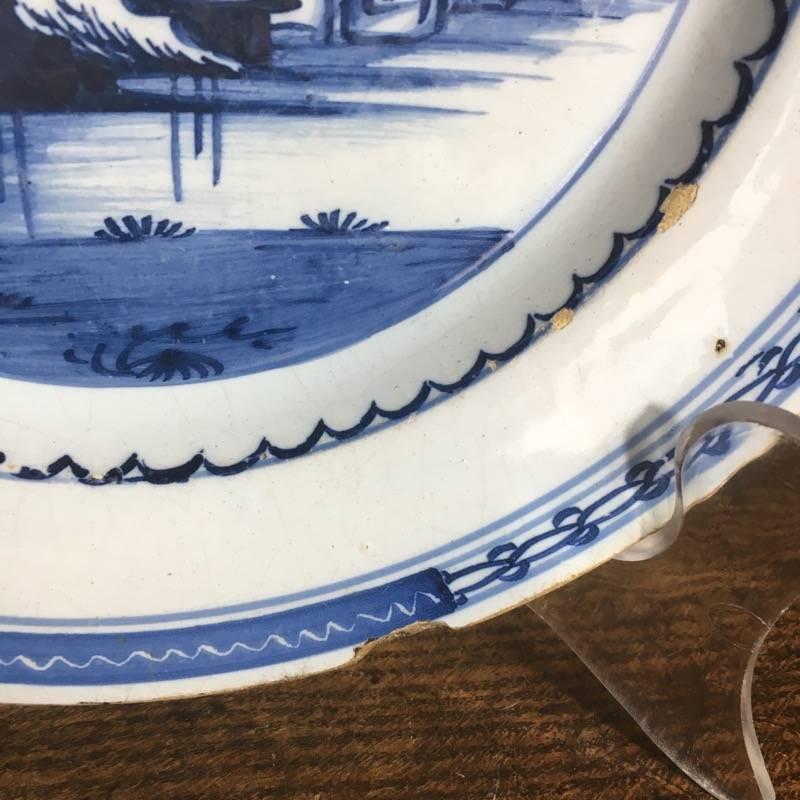 English delft plate, painted in glaze with a Chinese river landscape, including a large pagoda, within narrow geometric band borders. Attributed to London, circa 1770.

References: Ex-Rosenberg collection.
          