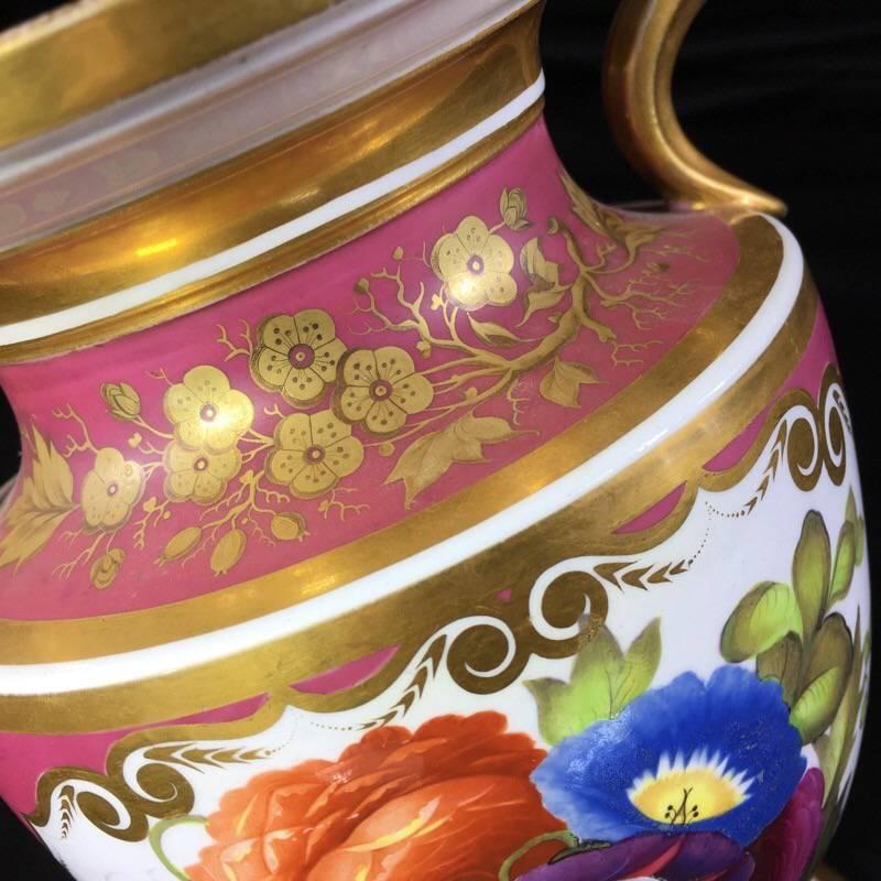 English bone china urn, the form taken from a Greek neck-Amphora, the gilt handle terminals with scrolls framing a face, the front with a panel of flowers reserved on a puce ground, the reverse with superb tooled gold flower spray with tooling.
