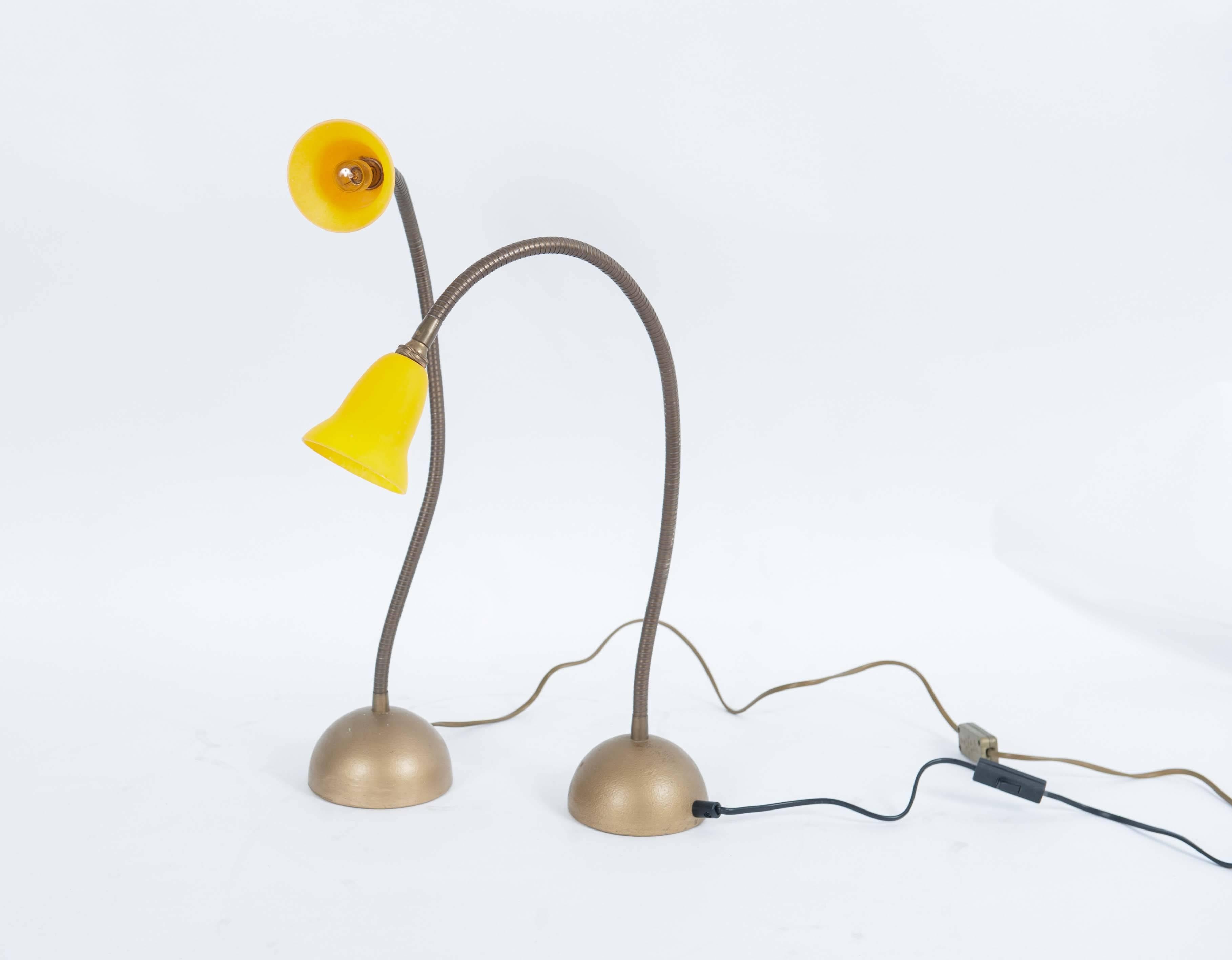 An elegant set of Dutch table lamps designed by Rob Nollet in the 1980s. 

The heavy cast iron base holds a bending arm in which the yellow glass lampshades have been fitted.

The bases and bending arms are flat gold-colored. Multi-functionality