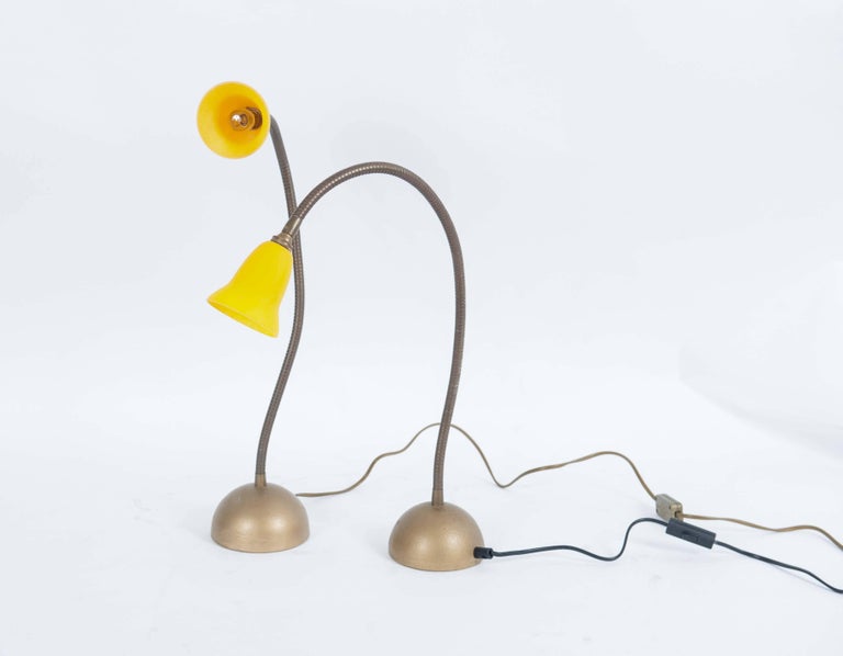 An elegant set of Dutch table lamps designed by Rob Nollet in the 1980s. 

The heavy cast iron base holds a bending arm in which the yellow glass lampshades have been fitted.

The bases and bending arms are flat gold-colored. Multi-functionality