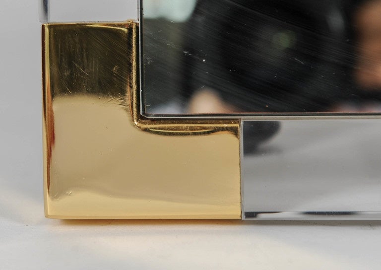 Wall mirror in a frame of lucite with brass corners.