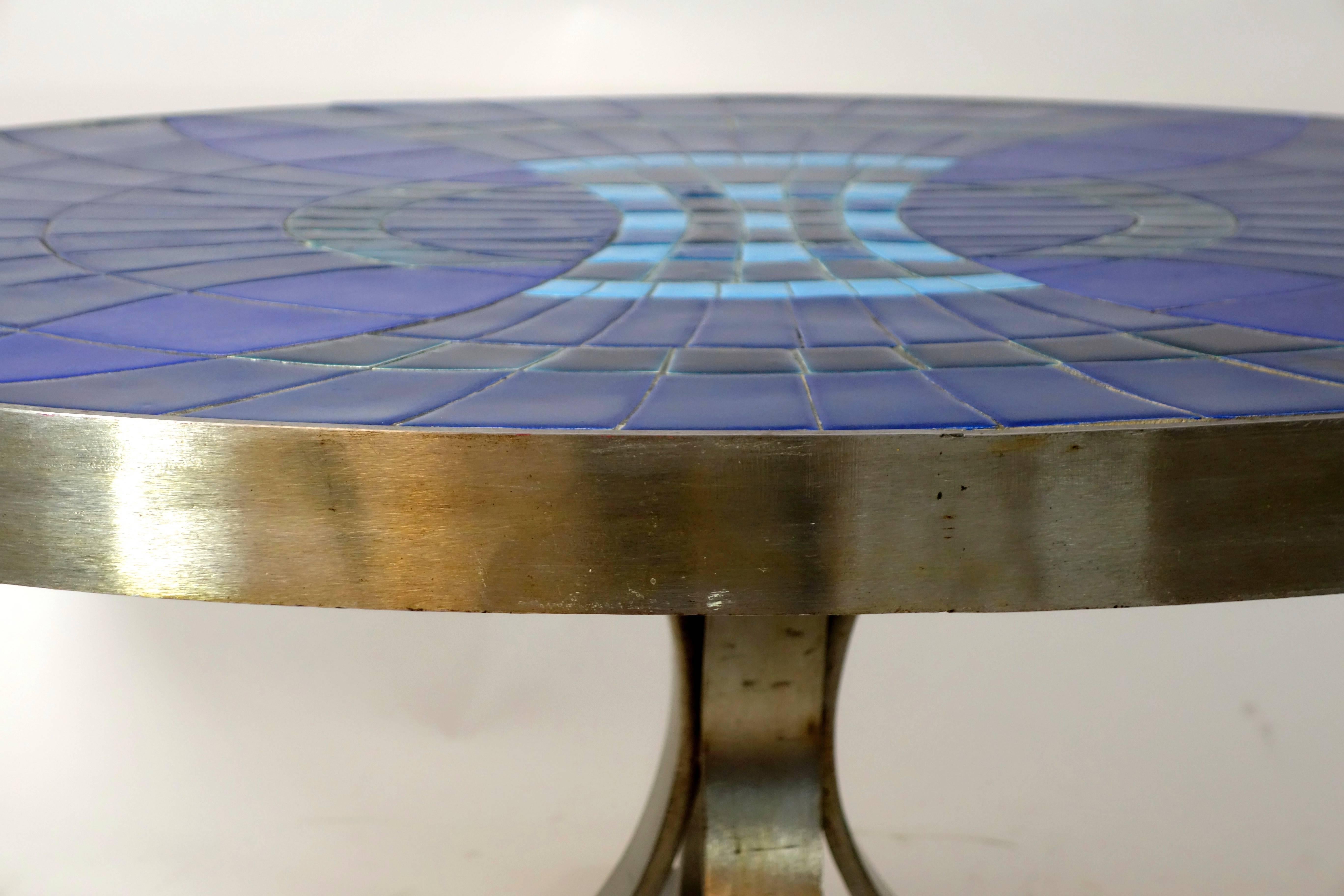 Cocktail table designed by Guy Trévoux in an oval shape. The top is inlaid with wonderful deep blue tiles in a refined pattern. The base of the table is made of chrome and has four feet. The table is signed. Guy Trévoux (1920-2011) was a French