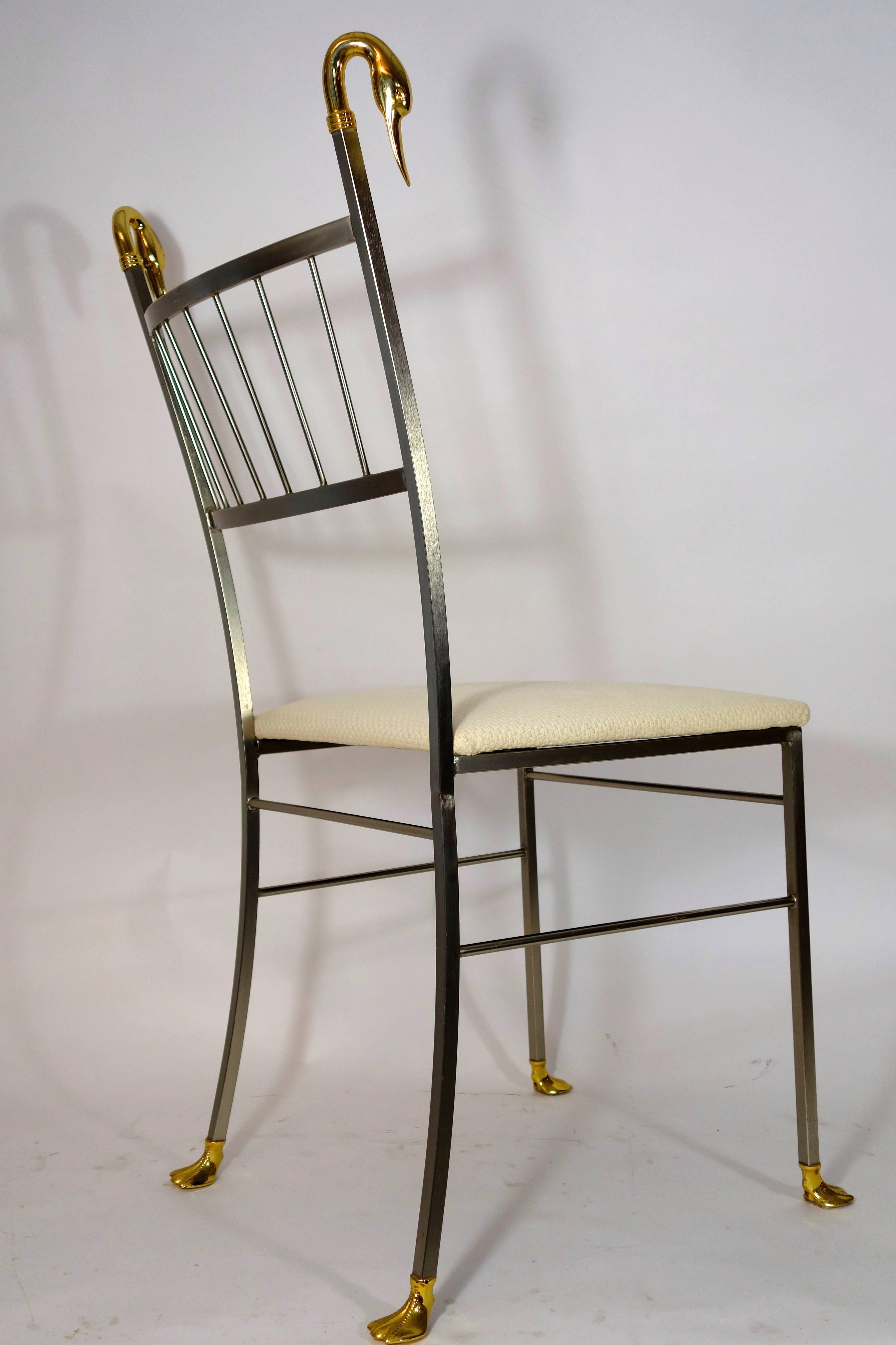 Set of four brass dining chairs in Hollywood Regency style. They have swan ornaments in the shape of swan heads on the top and swan feet on the bottom.
In a very good condition, but off-white upholstery has some stains. We leave it up to your own