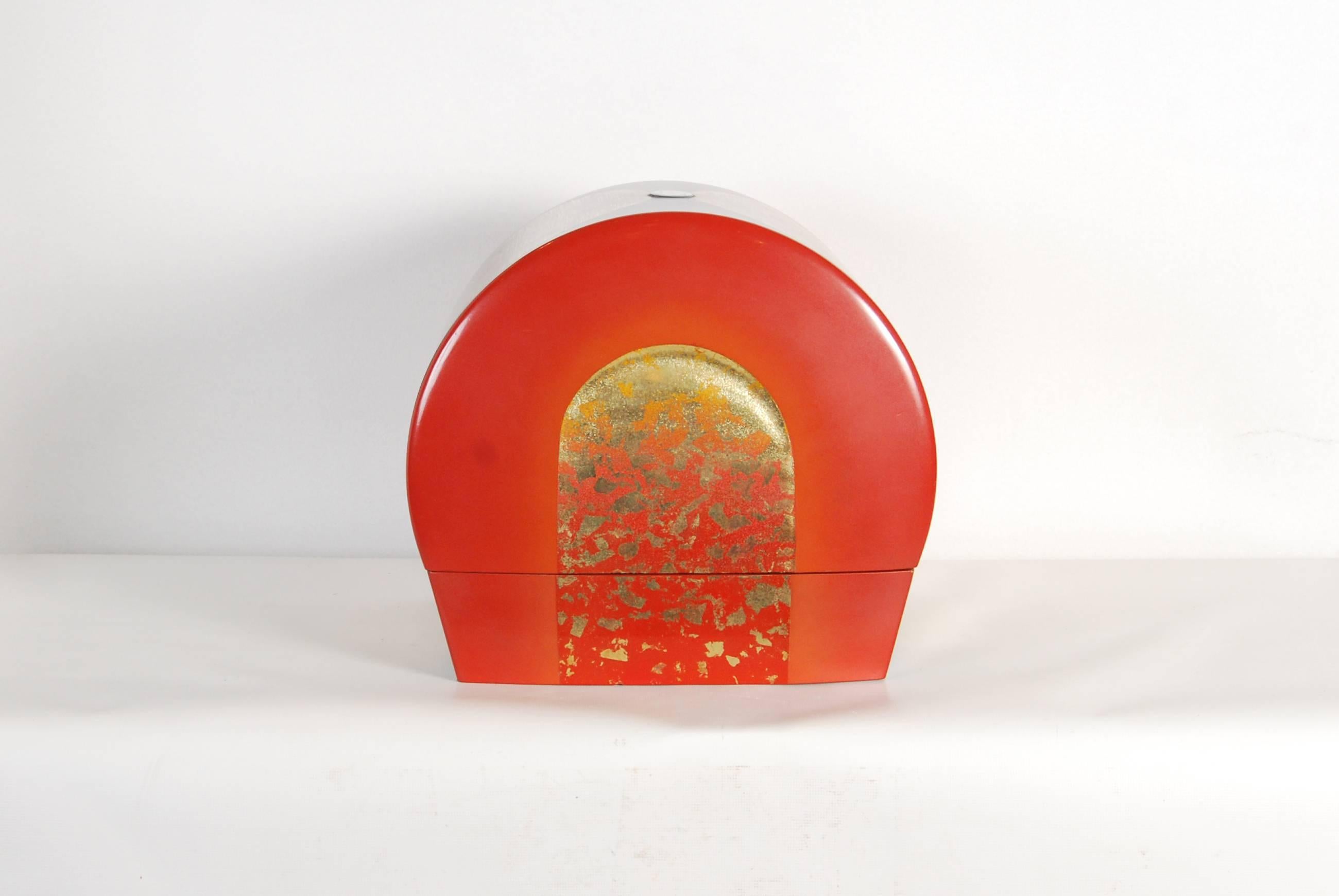 Contemporary Japanese red, blue and gold lacquer box of unusual arching form and heavy, carved construction by the known lacquer artist Yoshifumi Takeuchi.

Decorated on its lid with an inlaid mother-of-pearl finial and overall vibrantly coloured