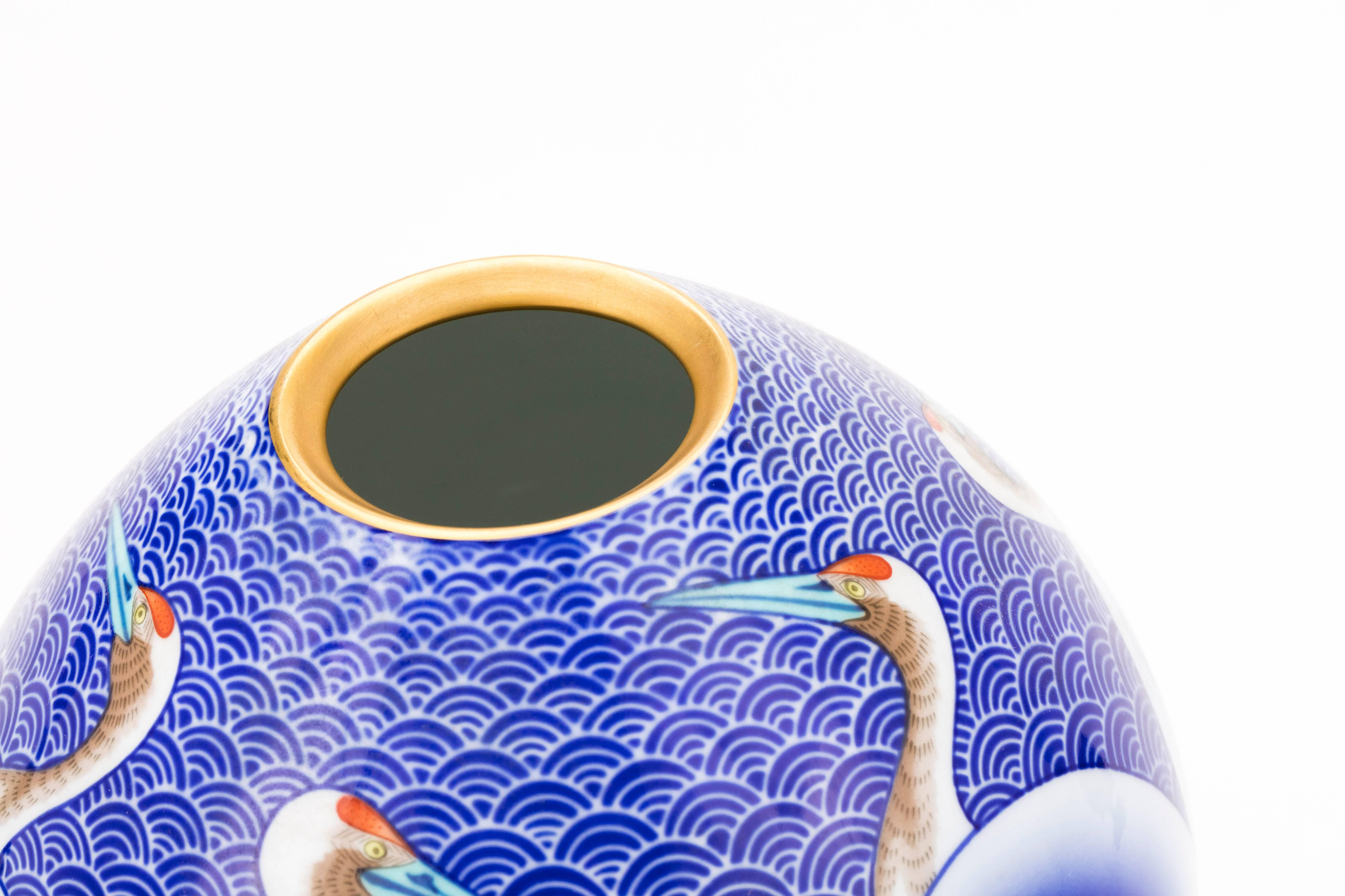 1960s Japanese Arita porcelain vase by Koransha Company, established in 1941. The vase is predominantly ultramarine blue, with blue underglaze stylized wave pattern in the background and cranes around the sides. The head and neck details of the