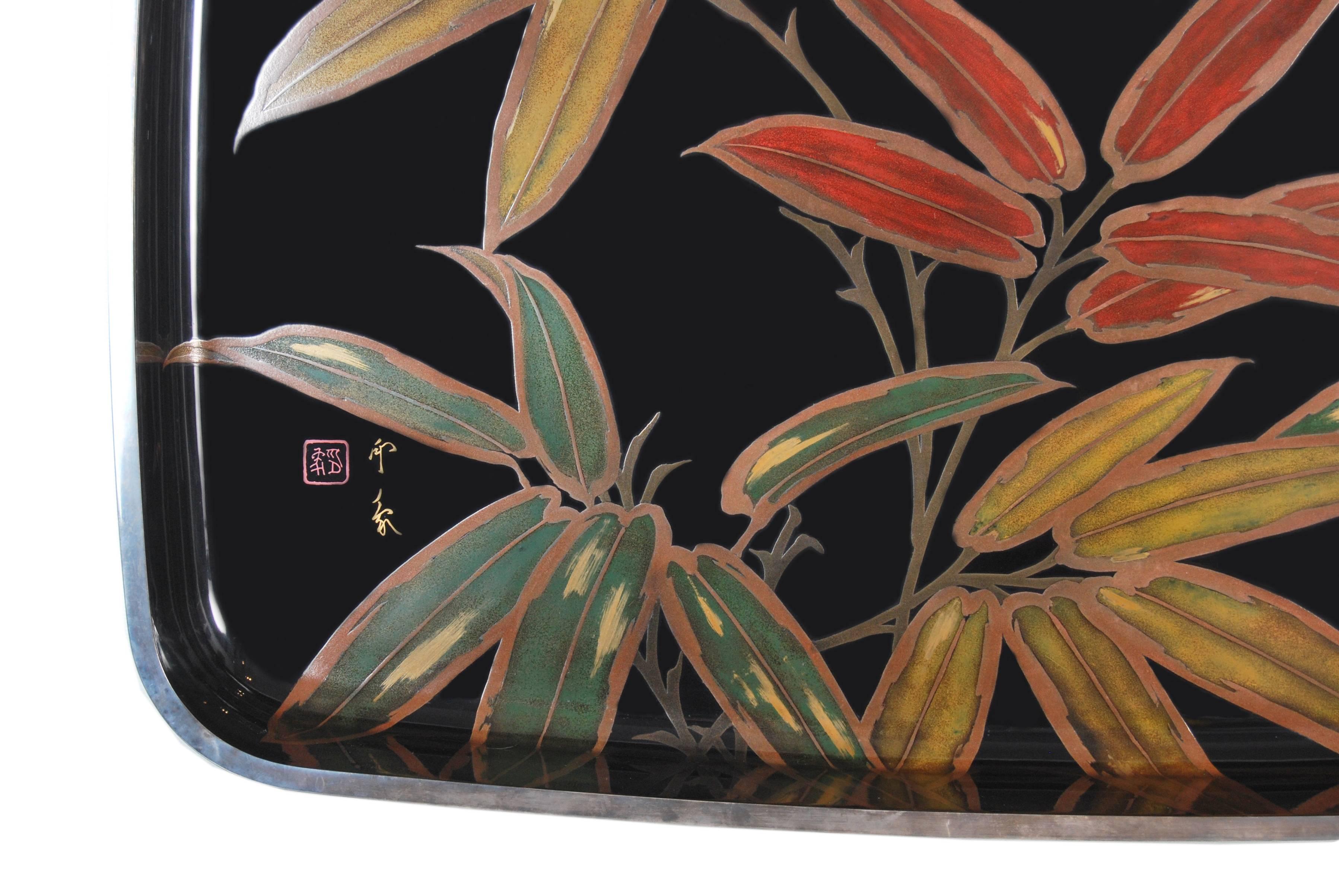 Japanese black lacquered tray of generous proportions with a bold design of bamboo leaves rendered in multicolored pigments and gold and silver maki-e lacquer. The top edge further decorated and protected by an applied solid silver rim, now