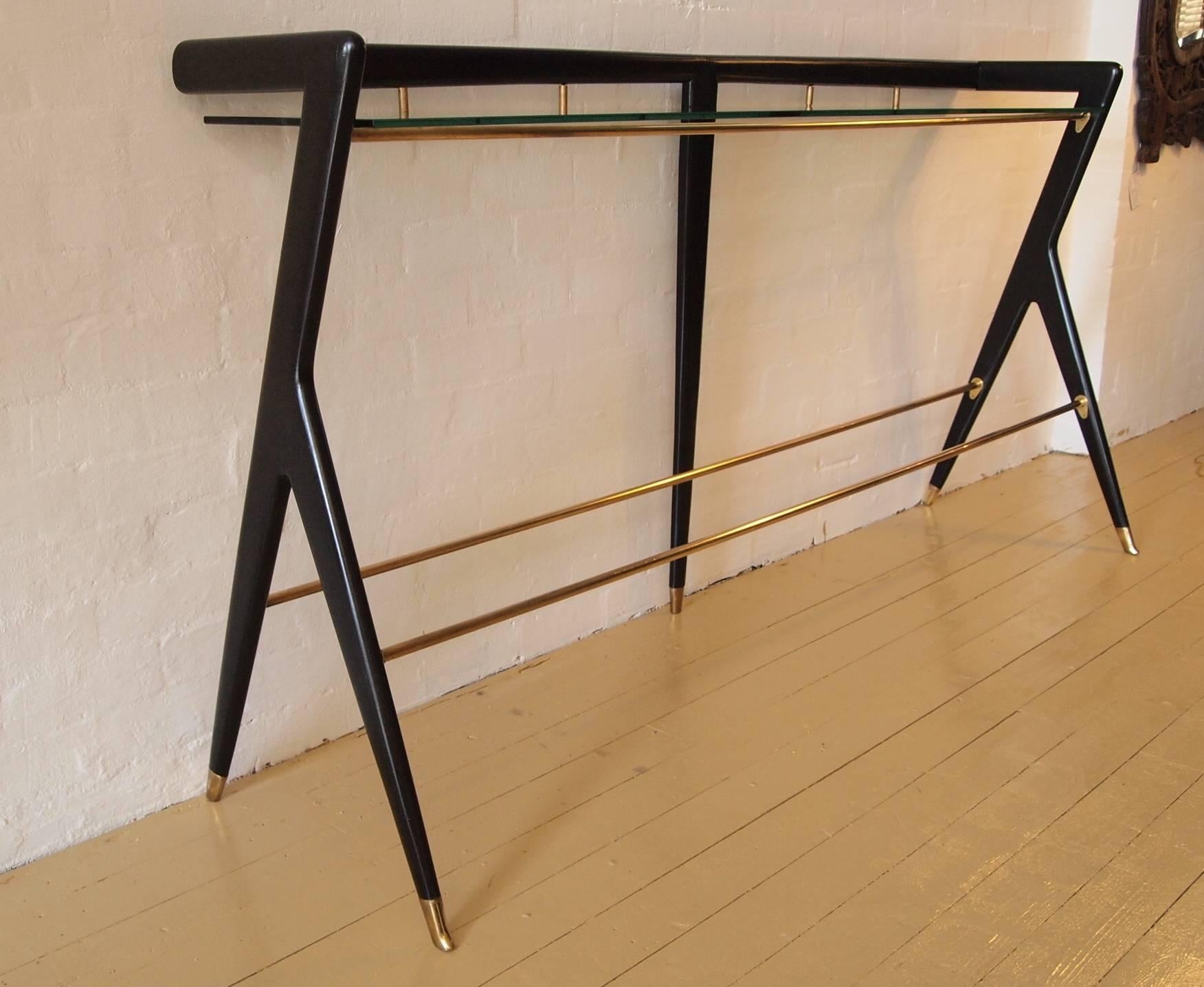 Ico and Luisa Parisi long console table, ebonized finish to wooden frame, with glass shelf 10mm thickness, brass rods and brass detailing. Italian, circa 1950.