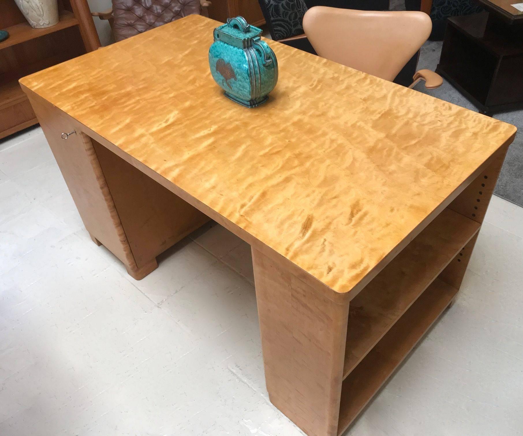 This is a rare find. Flame birch desk by BODAFORS Sweden. One side has an open bookshelf with adjustable shelving. The other side has a cabinet on the front and back. The front cabinet has a very unusual feature of a fold out work platform. A