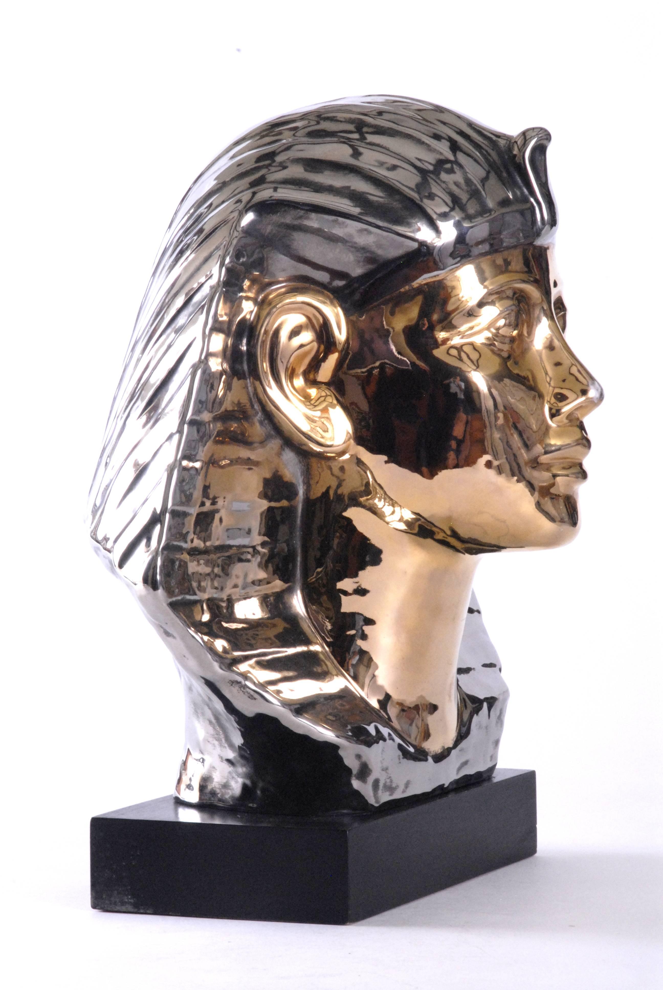 A brilliant Pharaoh's head with bright metallic glazes of silver and gold mounted on a black finished wooden base. Marked with a 'Z' on the base. Of large size this is an imposing decorative piece.