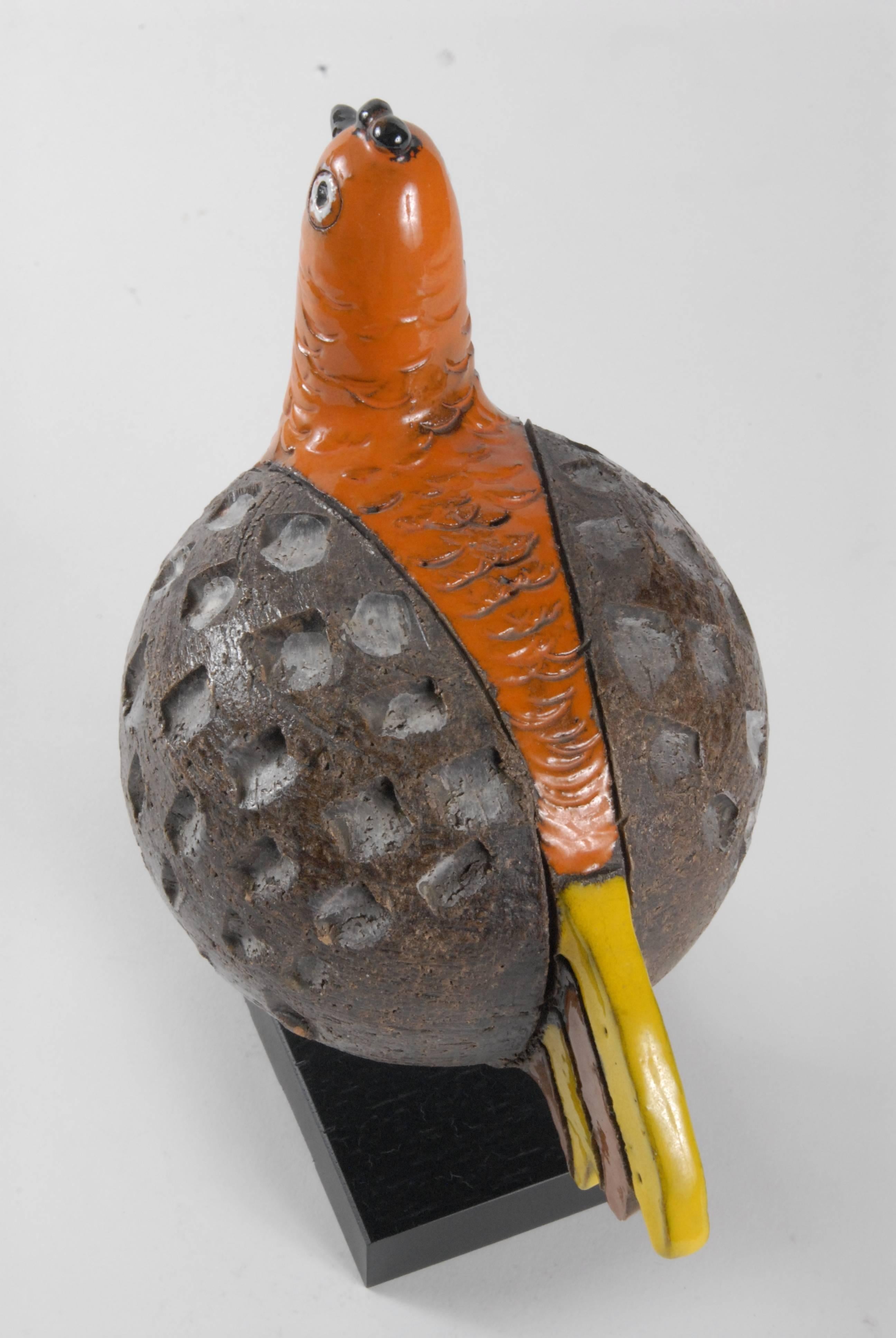 An Aldo Londi designed rare example bird, with impressed and Sgraffito patterns and orange, brown and yellow glazes on a wooden base.