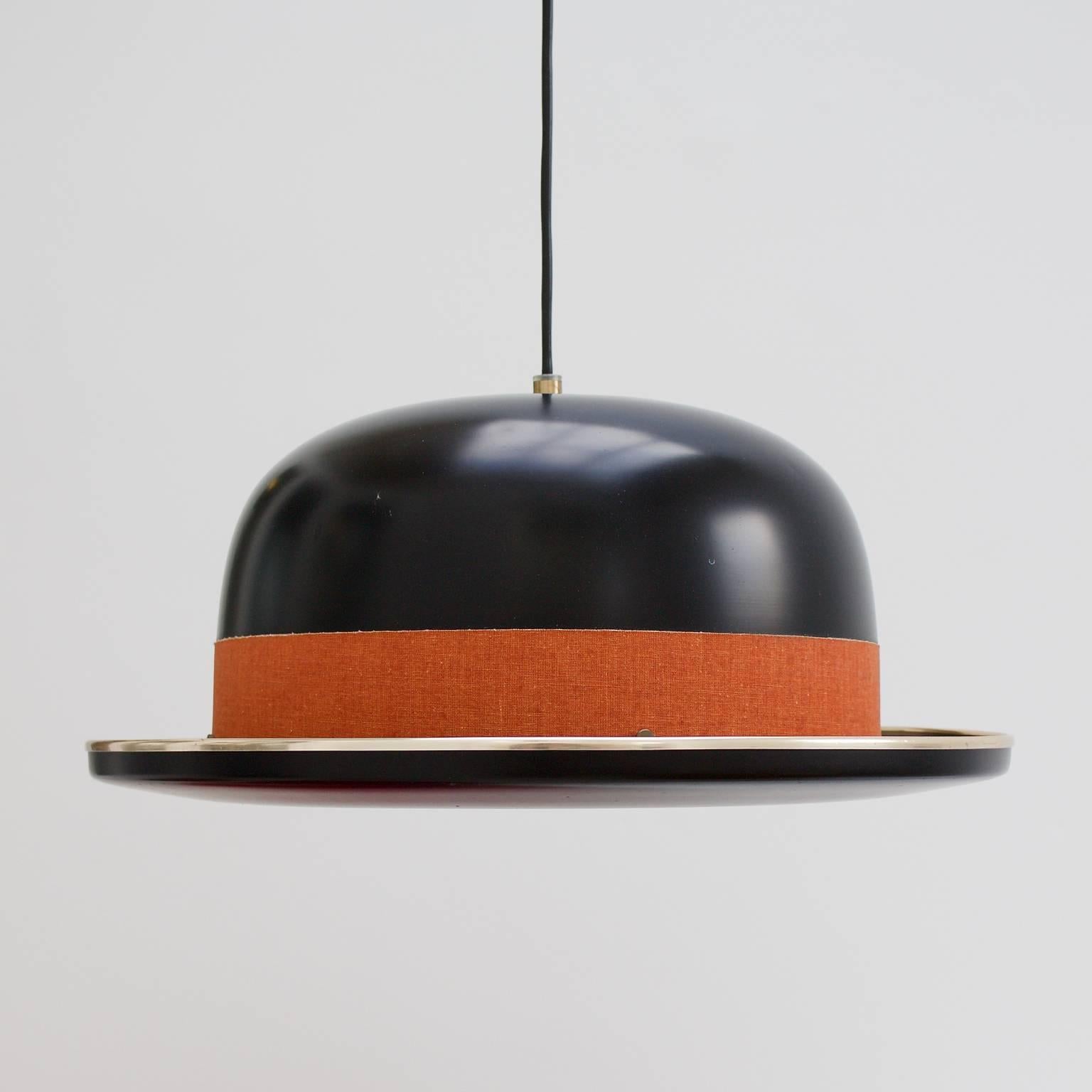 Bowler hat pendant lamp by Hans Agne Jakobsson for HAJ AB Markaryd, Sweden. Lacquered aluminium in black, with brass-plated trim, 1960s.

This unusual light has a surreal quality and is complete with its original linen hat band, in burnt orange, and