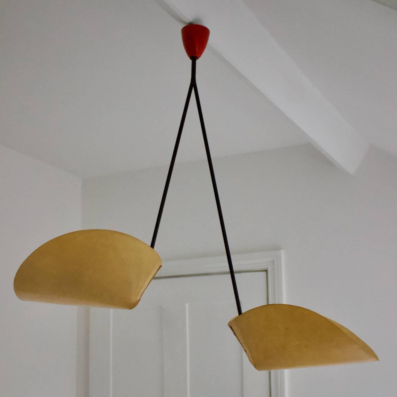 A stylish pendant light with two folded shades and a striking minimal or architectural silhouette, European, 1950s.

The light has a simple frame of tubular metal, painted black, with two light sources at different heights shielded from below by