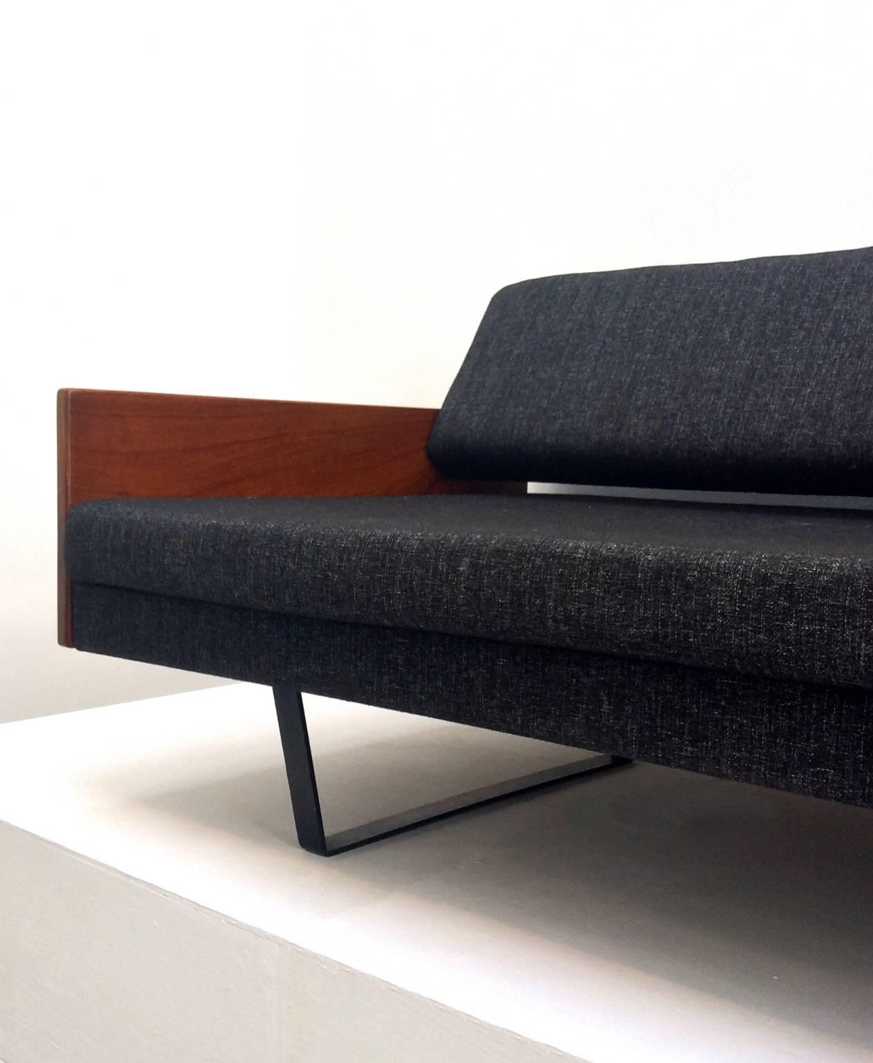Minimal daybed or sofa, by Robin Day, (1915-2010).

Elegant slim design with teak arms and adjustable back-rest, which can be turned away from the seat to create a single bed. Newly upholstered in dark grey wool, with black Pirelli webbing, to
