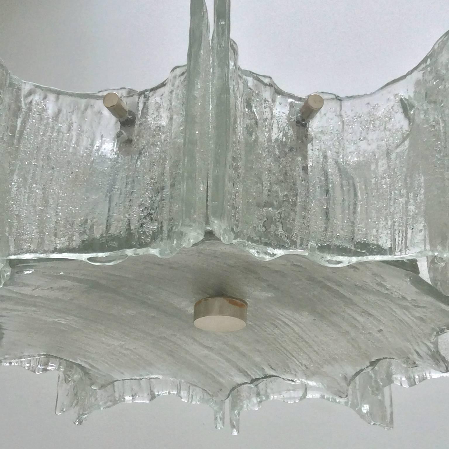 Chandelier or pendant light in heavy textured glass by Kaiser Leuchten, Germany, 1960s.

The fixture is made up of ten scalloped side panels over a single disc of the same textured glass. The panels have small grains of glass on the reverse side