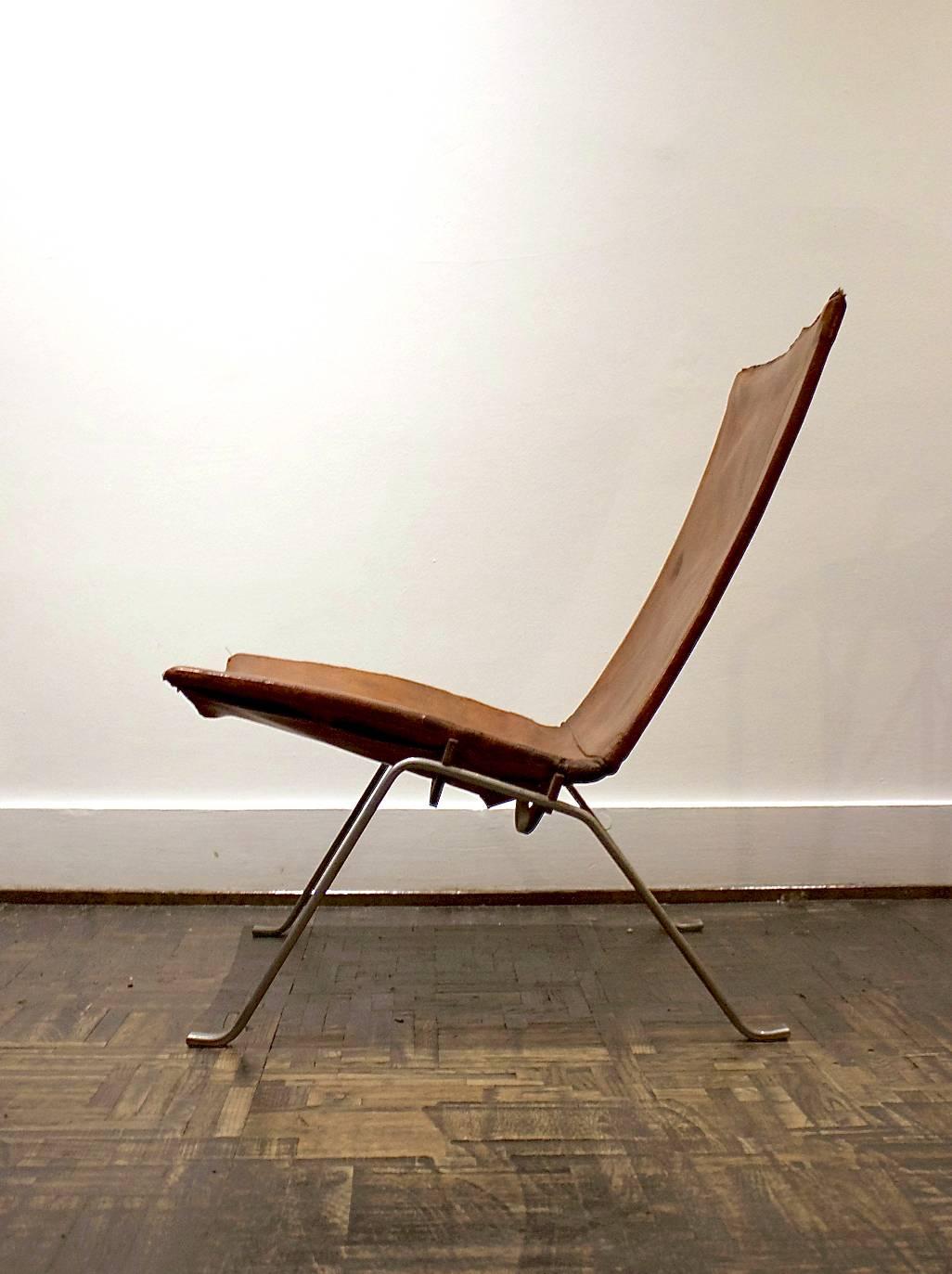 An early example of Poul Kjaerholm's 1956 design, model PK22. This piece, manufactured by E Kold Christensen, has the original nickel-plated steel frame and tan leather. 

The chair shows a highly developed patina to both the leather and the