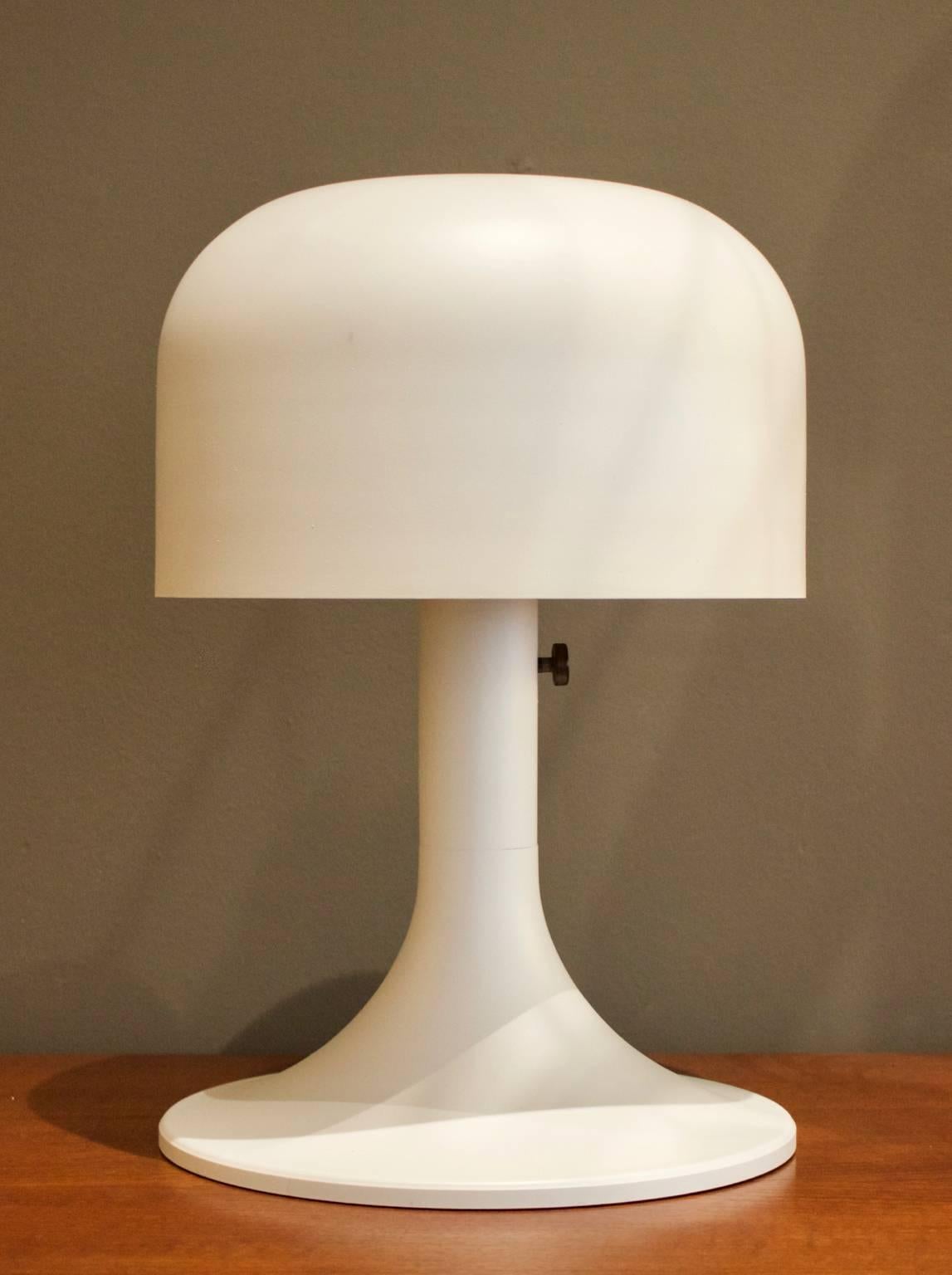 Table lamp with spun aluminium mushroom shade over a tulip base. 

Redolent of designs by Stilnovo, Guzzini or Sonneman, this is a simple piece, nicely made and a little heavier than its style suggests. The light from the bulb emerges above and