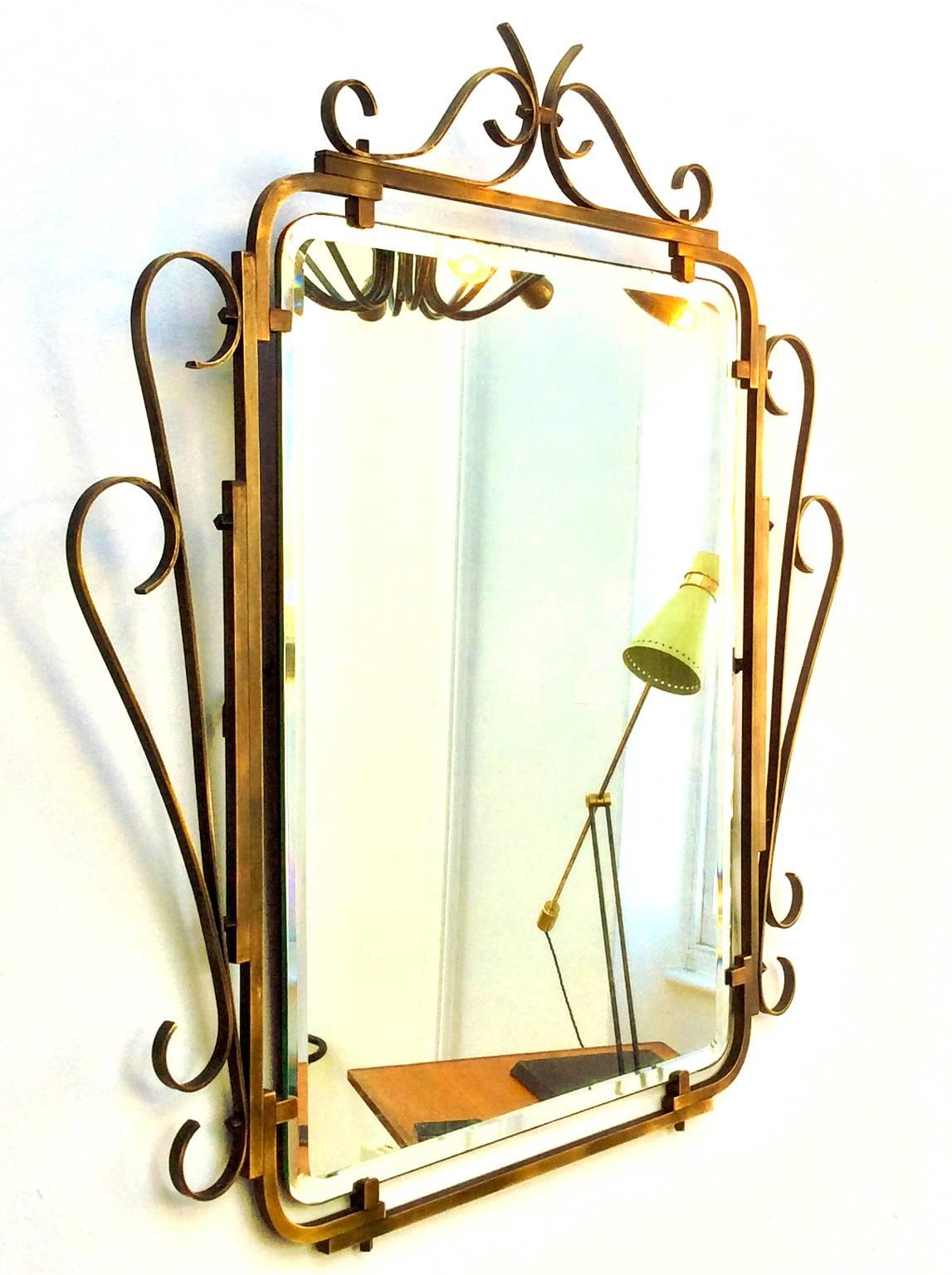 Wall mirror with bevelled glass and decorative brass frame. Mid-20th century, Art Deco style, European.  

The frame is nicely engineered, with small square nuts and screws holding the brass together.  A heavy piece with hanging chain.  The frame