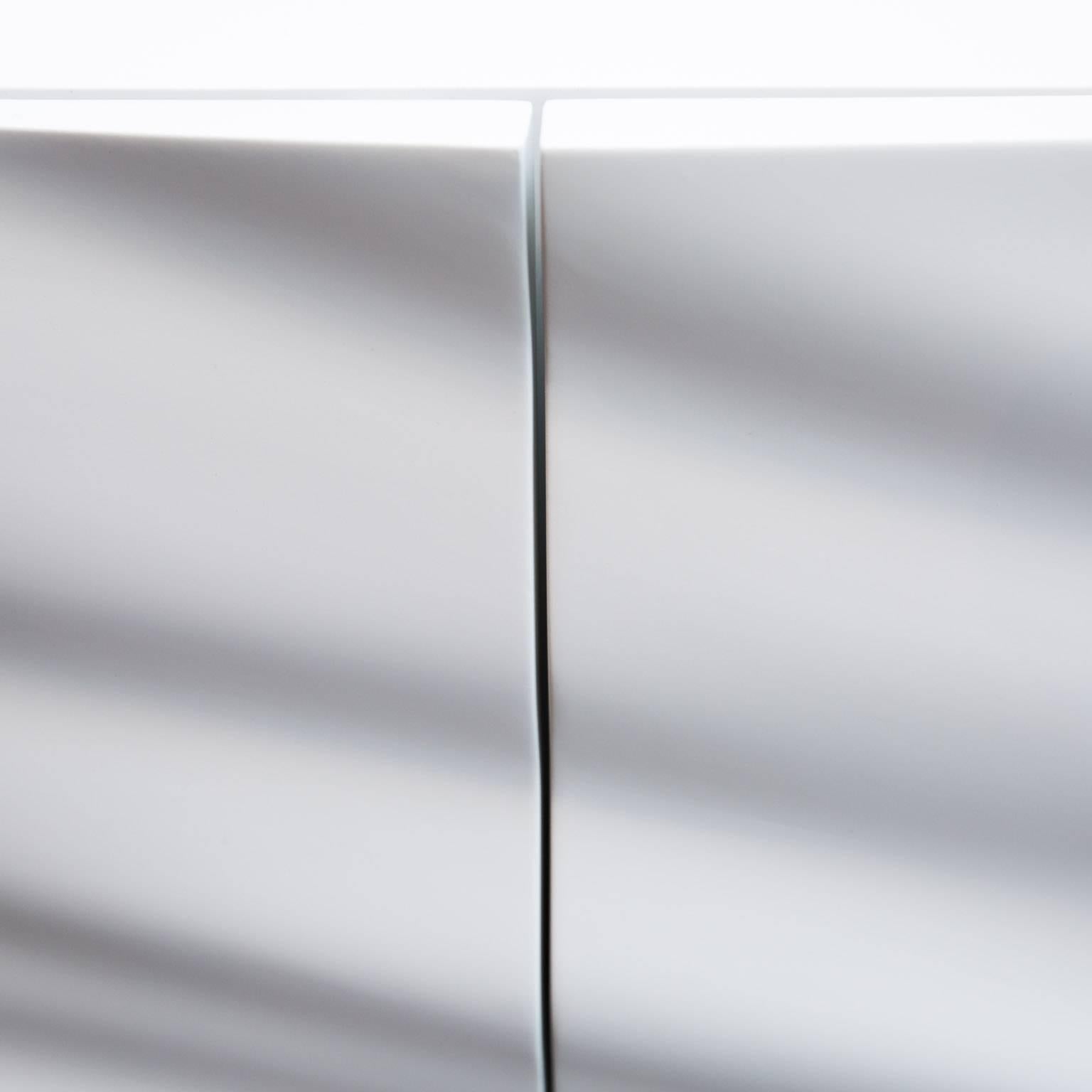 Designed by custom cabinetmaker Sam Poulos, this one-of-a-kind credenza is made of cad-designed medium density fiberboard. Finished in a satin white lacquer with brushed aluminum legs. Its three compartments include two deep drawers left and right