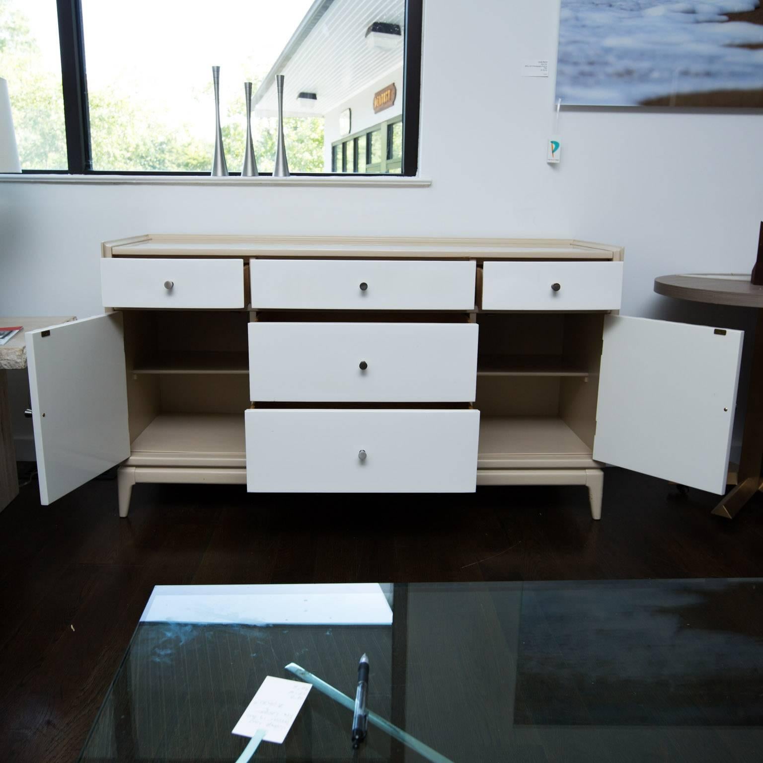 Nice vintage piece that's been given anew life with new brushed aluminum drawer pulls and a contemporary two-toned beige and white lacquer. Could easily double as a dresser.